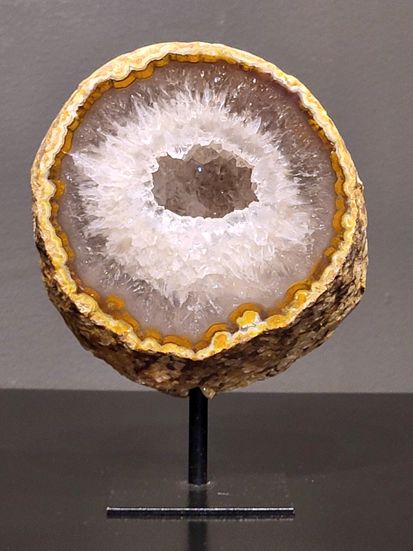 Agaat op standaard, 884 gram, 16cm hg. en 11cm br.  31,- euro, nr. 14
Agaat is een veelzijdige edelsteen die bekend staat om zijn prachtige kleurbanden en patronen. Het is een variëteit van het mineraal kwarts, meer specifiek chalcedoon, en wordt vaak gebruikt in sieraden en als decoratieve steen. 
Algemene kenmerken:
Agaat is een microkristallijne vorm van kwarts, bestaande uit microscopisch kleine kristallen. 
Kleuren en patronen:
Agaat komt voor in vele kleuren, vaak met banden of lagen in verschillende tinten. 
Agaat is een populaire keuze voor het maken van kettingen, armbanden, ringen en andere sieraden vanwege de esthetische aantrekkingskracht en duurzaamheid. 
Spirituele eigenschappen:
Agaat wordt vaak geassocieerd met aardende, stabiliserende en beschermende eigenschappen. 
Helende werking:
Er wordt aangenomen dat agaat kan helpen bij het verminderen van stress, het bevorderen van emotioneel evenwicht en het versterken van het zelfvertrouwen. 
Verzorging van agaat:
Agaat is relatief gemakkelijk te onderhouden. Het kan worden gereinigd met lauw water, de rook van witte salie of palo santo, of door het op een hematiet- of bergkristal-cluster te plaatsen. 

-	Kunstgalerie-Arnold -