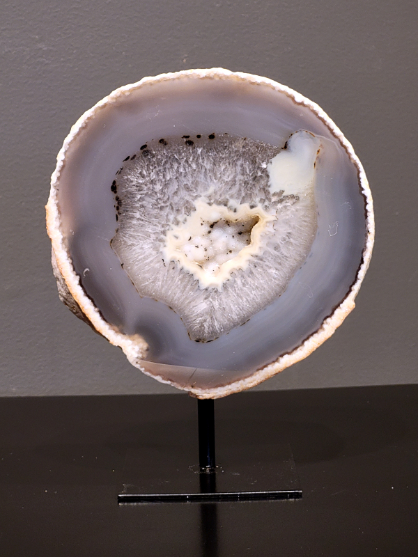 Agaat op standaard, 1,1kg, 17cm hg. en 12cm br. 40,- euro, nr. 5
Agaat is een veelzijdige edelsteen die bekend staat om zijn prachtige kleurbanden en patronen. Het is een variëteit van het mineraal kwarts, meer specifiek chalcedoon, en wordt vaak gebruikt in sieraden en als decoratieve steen. 
Algemene kenmerken:
Agaat is een microkristallijne vorm van kwarts, bestaande uit microscopisch kleine kristallen. 
Kleuren en patronen:
Agaat komt voor in vele kleuren, vaak met banden of lagen in verschillende tinten. 
Agaat is een populaire keuze voor het maken van kettingen, armbanden, ringen en andere sieraden vanwege de esthetische aantrekkingskracht en duurzaamheid. 
Spirituele eigenschappen:
Agaat wordt vaak geassocieerd met aardende, stabiliserende en beschermende eigenschappen. 
Helende werking:
Er wordt aangenomen dat agaat kan helpen bij het verminderen van stress, het bevorderen van emotioneel evenwicht en het versterken van het zelfvertrouwen. 
Verzorging van agaat:
Agaat is relatief gemakkelijk te onderhouden. Het kan worden gereinigd met lauw water, de rook van witte salie of palo santo, of door het op een hematiet- of bergkristal-cluster te plaatsen. 

-	Kunstgalerie-Arnold -