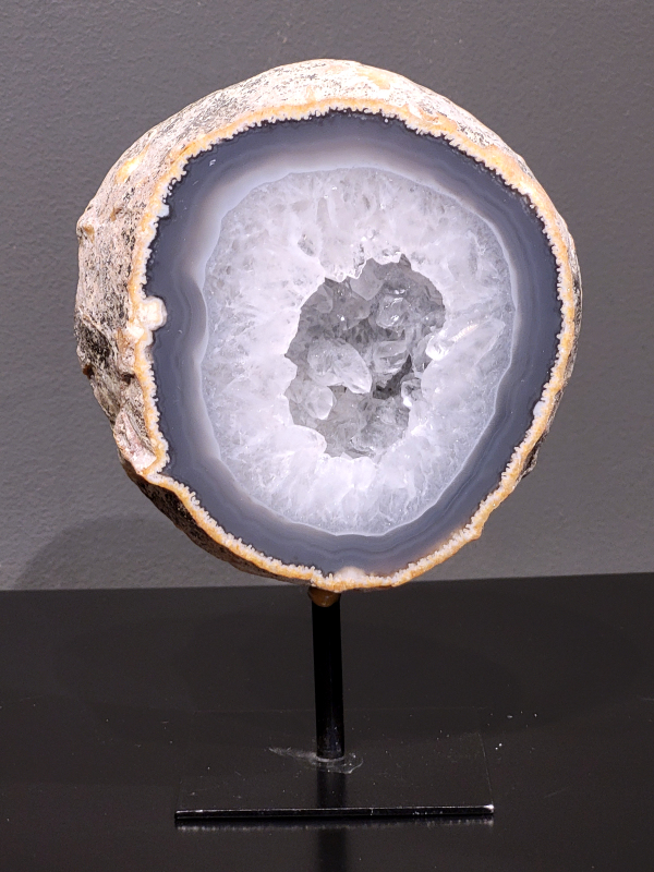 Agaat op standaard, 1,4 kg., 21cm hg. en 16cm br. 49,- euro, nr. 3
Agaat is een veelzijdige edelsteen die bekend staat om zijn prachtige kleurbanden en patronen. Het is een variëteit van het mineraal kwarts, meer specifiek chalcedoon, en wordt vaak gebruikt in sieraden en als decoratieve steen. 
Algemene kenmerken:
Agaat is een microkristallijne vorm van kwarts, bestaande uit microscopisch kleine kristallen. 
Kleuren en patronen:
Agaat komt voor in vele kleuren, vaak met banden of lagen in verschillende tinten. 
Agaat is een populaire keuze voor het maken van kettingen, armbanden, ringen en andere sieraden vanwege de esthetische aantrekkingskracht en duurzaamheid. 
Spirituele eigenschappen:
Agaat wordt vaak geassocieerd met aardende, stabiliserende en beschermende eigenschappen. 
Helende werking:
Er wordt aangenomen dat agaat kan helpen bij het verminderen van stress, het bevorderen van emotioneel evenwicht en het versterken van het zelfvertrouwen. 
Verzorging van agaat:
Agaat is relatief gemakkelijk te onderhouden. Het kan worden gereinigd met lauw water, de rook van witte salie of palo santo, of door het op een hematiet- of bergkristal-cluster te plaatsen. 

-	Kunstgalerie-Arnold -