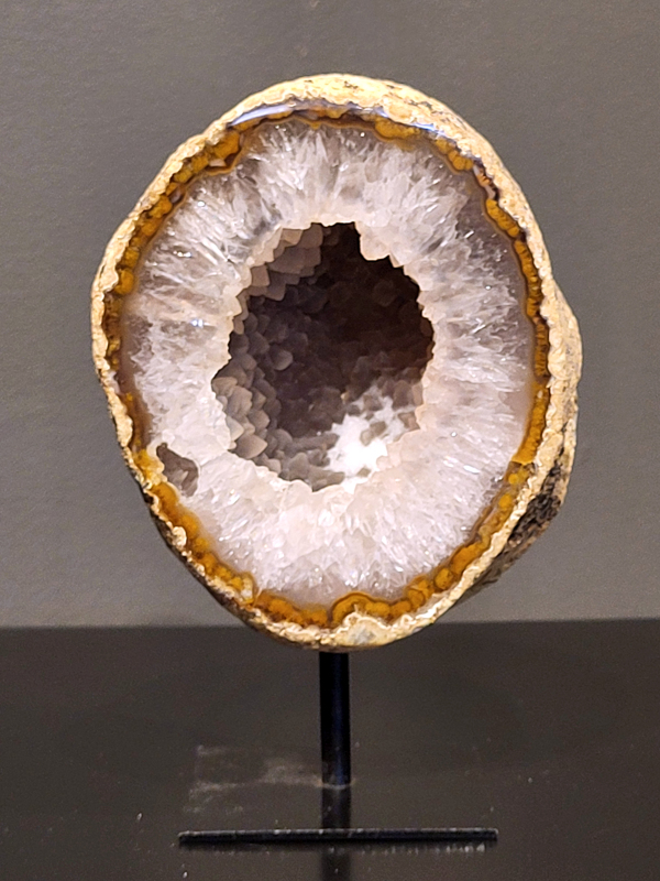 Agaat op standaard, 872 gram, 16cm hg. en 10cm br.  31,- euro, nr. 28
Agaat is een veelzijdige edelsteen die bekend staat om zijn prachtige kleurbanden en patronen. Het is een variëteit van het mineraal kwarts, meer specifiek chalcedoon, en wordt vaak gebruikt in sieraden en als decoratieve steen. 
Algemene kenmerken:
Agaat is een microkristallijne vorm van kwarts, bestaande uit microscopisch kleine kristallen. 
Kleuren en patronen:
Agaat komt voor in vele kleuren, vaak met banden of lagen in verschillende tinten. 
Agaat is een populaire keuze voor het maken van kettingen, armbanden, ringen en andere sieraden vanwege de esthetische aantrekkingskracht en duurzaamheid. 
Spirituele eigenschappen:
Agaat wordt vaak geassocieerd met aardende, stabiliserende en beschermende eigenschappen. 
Helende werking:
Er wordt aangenomen dat agaat kan helpen bij het verminderen van stress, het bevorderen van emotioneel evenwicht en het versterken van het zelfvertrouwen. 
Verzorging van agaat:
Agaat is relatief gemakkelijk te onderhouden. Het kan worden gereinigd met lauw water, de rook van witte salie of palo santo, of door het op een hematiet- of bergkristal-cluster te plaatsen. 

-	Kunstgalerie-Arnold -