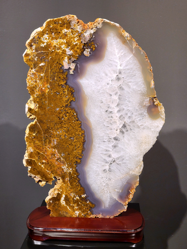 Agaat op standaard, 4,8 kg., 55cm hg. en 35 cm br. 260,- euro, nr. 32
Agaat is een veelzijdige edelsteen die bekend staat om zijn prachtige kleurbanden en patronen. Het is een variëteit van het mineraal kwarts, meer specifiek chalcedoon, en wordt vaak gebruikt in sieraden en als decoratieve steen. 
Algemene kenmerken:
Agaat is een microkristallijne vorm van kwarts, bestaande uit microscopisch kleine kristallen. 
Kleuren en patronen:
Agaat komt voor in vele kleuren, vaak met banden of lagen in verschillende tinten. 
Agaat is een populaire keuze voor het maken van kettingen, armbanden, ringen en andere sieraden vanwege de esthetische aantrekkingskracht en duurzaamheid. 
Spirituele eigenschappen:
Agaat wordt vaak geassocieerd met aardende, stabiliserende en beschermende eigenschappen. 
Helende werking:
Er wordt aangenomen dat agaat kan helpen bij het verminderen van stress, het bevorderen van emotioneel evenwicht en het versterken van het zelfvertrouwen. 
Verzorging van agaat:
Agaat is relatief gemakkelijk te onderhouden. Het kan worden gereinigd met lauw water, de rook van witte salie of palo santo, of door het op een hematiet- of bergkristal-cluster te plaatsen. 

-	Kunstgalerie-Arnold -