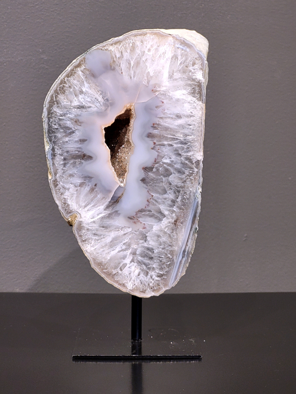 Agaat op standaard, 1,4 kg., 19cm hg. en 13cm br. 48,- euro, nr. 1
Agaat is een veelzijdige edelsteen die bekend staat om zijn prachtige kleurbanden en patronen. Het is een variëteit van het mineraal kwarts, meer specifiek chalcedoon, en wordt vaak gebruikt in sieraden en als decoratieve steen. 
Algemene kenmerken:
Agaat is een microkristallijne vorm van kwarts, bestaande uit microscopisch kleine kristallen. 
Kleuren en patronen:
Agaat komt voor in vele kleuren, vaak met banden of lagen in verschillende tinten. 
Agaat is een populaire keuze voor het maken van kettingen, armbanden, ringen en andere sieraden vanwege de esthetische aantrekkingskracht en duurzaamheid. 
Spirituele eigenschappen:
Agaat wordt vaak geassocieerd met aardende, stabiliserende en beschermende eigenschappen. 
Helende werking:
Er wordt aangenomen dat agaat kan helpen bij het verminderen van stress, het bevorderen van emotioneel evenwicht en het versterken van het zelfvertrouwen. 
Verzorging van agaat:
Agaat is relatief gemakkelijk te onderhouden. Het kan worden gereinigd met lauw water, de rook van witte salie of palo santo, of door het op een hematiet- of bergkristal-cluster te plaatsen. 

-Kunstgalerie-Arnold -