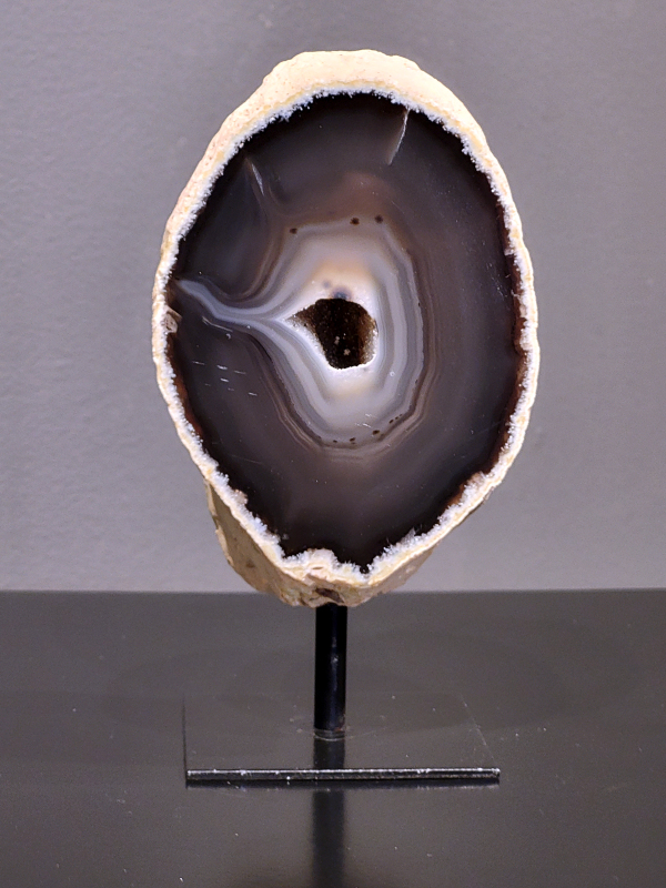 Agaat op standaard, 604 gram, 15cm hg. en 8 cm br. 21,- euro, nr. 21
Agaat is een veelzijdige edelsteen die bekend staat om zijn prachtige kleurbanden en patronen. Het is een variëteit van het mineraal kwarts, meer specifiek chalcedoon, en wordt vaak gebruikt in sieraden en als decoratieve steen. 
Algemene kenmerken:
Agaat is een microkristallijne vorm van kwarts, bestaande uit microscopisch kleine kristallen. 
Kleuren en patronen:
Agaat komt voor in vele kleuren, vaak met banden of lagen in verschillende tinten. 
Agaat is een populaire keuze voor het maken van kettingen, armbanden, ringen en andere sieraden vanwege de esthetische aantrekkingskracht en duurzaamheid. 
Spirituele eigenschappen:
Agaat wordt vaak geassocieerd met aardende, stabiliserende en beschermende eigenschappen. 
Helende werking:
Er wordt aangenomen dat agaat kan helpen bij het verminderen van stress, het bevorderen van emotioneel evenwicht en het versterken van het zelfvertrouwen. 
Verzorging van agaat:
Agaat is relatief gemakkelijk te onderhouden. Het kan worden gereinigd met lauw water, de rook van witte salie of palo santo, of door het op een hematiet- of bergkristal-cluster te plaatsen. 

-	Kunstgalerie-Arnold -