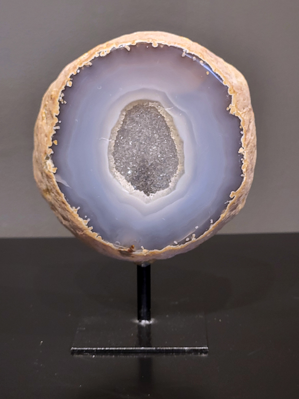 Agaat op standaard, 864 gram, 14cm hg. en 11cm br.  30,- euro, nr. 24
Agaat is een veelzijdige edelsteen die bekend staat om zijn prachtige kleurbanden en patronen. Het is een variëteit van het mineraal kwarts, meer specifiek chalcedoon, en wordt vaak gebruikt in sieraden en als decoratieve steen. 
Algemene kenmerken:
Agaat is een microkristallijne vorm van kwarts, bestaande uit microscopisch kleine kristallen. 
Kleuren en patronen:
Agaat komt voor in vele kleuren, vaak met banden of lagen in verschillende tinten. 
Agaat is een populaire keuze voor het maken van kettingen, armbanden, ringen en andere sieraden vanwege de esthetische aantrekkingskracht en duurzaamheid. 
Spirituele eigenschappen:
Agaat wordt vaak geassocieerd met aardende, stabiliserende en beschermende eigenschappen. 
Helende werking:
Er wordt aangenomen dat agaat kan helpen bij het verminderen van stress, het bevorderen van emotioneel evenwicht en het versterken van het zelfvertrouwen. 
Verzorging van agaat:
Agaat is relatief gemakkelijk te onderhouden. Het kan worden gereinigd met lauw water, de rook van witte salie of palo santo, of door het op een hematiet- of bergkristal-cluster te plaatsen. 

-	Kunstgalerie-Arnold -
