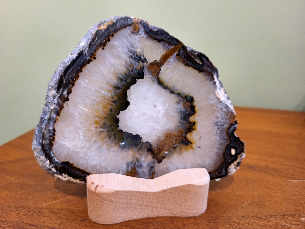 Agaatschijf, waxinelicht,13cm breed, 20,- euro, nr. 41
Beschrijving Agaat.

Agaat is een veelzijdige edelsteen die bekend staat om zijn prachtige kleurbanden en patronen. Het is een variëteit van het mineraal kwarts, meer specifiek chalcedoon, en wordt vaak gebruikt in sieraden en als decoratieve steen. 
Algemene kenmerken:
Samenstelling:
Agaat is een microkristallijne vorm van kwarts, bestaande uit microscopisch kleine kristallen. 
Kleuren en patronen:
Agaat komt voor in vele kleuren, vaak met banden of lagen in verschillende tinten. 
Hardheid:
Agaat heeft een hardheid van 6,5 tot 7 op de schaal van Mohs, wat betekent dat het een relatief duurzame steen is. 
Herkomst:
De naam "agaat" is afgeleid van de rivier Achates (nu Drillo) op Sicilië, waar de steen voor het eerst werd ontdekt. 
Eigenschappen en toepassingen:
Sieraden:
Agaat is een populaire keuze voor het maken van kettingen, armbanden, ringen en andere sieraden vanwege de esthetische aantrekkingskracht en duurzaamheid. 
Spirituele eigenschappen:
Agaat wordt vaak geassocieerd met aardende, stabiliserende en beschermende eigenschappen. 
Helende werking:
Er wordt aangenomen dat agaat kan helpen bij het verminderen van stress, het bevorderen van emotioneel evenwicht en het versterken van het zelfvertrouwen. 
Andere toepassingen:
Agaat wordt ook gebruikt in decoratieve objecten, zoals schijven en tafels, en werd in het verleden gebruikt in oude culturen voor bescherming en geluk. 
Soorten agaat:
Er zijn veel verschillende soorten agaat, elk met hun eigen unieke kenmerken en eigenschappen, zoals:
Botswana agaat: Bekend om zijn zachte, kalmerende energie en kan helpen bij het loslaten van negatieve emoties. 
Witte agaat: Vaak geassocieerd met innerlijke rust en evenwicht. 
Grijze agaat: Kan helpen bij het stellen van orde en het vinden van stabiliteit. 
Agaat geode: Kan rustgevend werken en chaos tegengaan. 
Verzorging van agaat:
Agaat is relatief gemakkelijk te onderhouden. Het kan worden gereinigd met lauw water, de rook van witte salie of palo santo, of door het op een hematiet- of bergkristal-cluster te plaatsen.