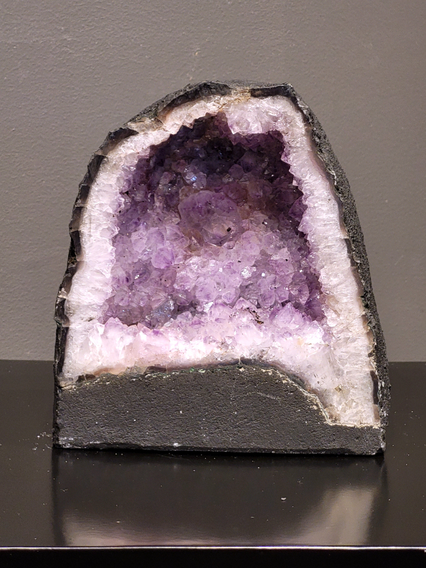 Amethist, 3,1 kg., 17cm hg. en 15cm br. 54,- euro, nr. 8
Beschrijving Amethist.
Amethist is een paarse variëteit van kwarts, bekend om zijn kalmerende en spirituele eigenschappen. De kleur varieert van licht lila tot diep violet en wordt veroorzaakt door sporen van ijzer en andere elementen. Amethist wordt al eeuwenlang gewaardeerd, zowel vanwege zijn esthetische schoonheid als zijn vermeende genezende en beschermende krachten. 
Amethist is een kwartskristal, vaak te vinden in geodes (holtes in gesteente) of als afzonderlijke kristallen. 
De kleur varieert van lichtpaars tot diep violet, soms met roze of blauwe tinten. 
De kleurintensiteit kan variëren, waarbij donkerdere amethisten vaak als kwalitatief worden beschouwd. 
Soms vertoont amethist dichroïsme, waarbij je verschillende kleuren kunt zien wanneer je de steen in het licht draait. 

Vindplaatsen:
Amethist wordt gevonden in verschillende delen van de wereld, waaronder Brazilië, Uruguay, Zambia, Madagaskar, Rusland en Canada.
Het wordt vaak gevonden in bergachtige gebieden. 

Gebruik:
Amethist wordt gebruikt in sieraden, decoratieve objecten en als helende steen. 
Het wordt vaak gedragen als hanger, ring of armband, of geplaatst in ruimtes om de energie te zuiveren. 
Amethist wordt ook gebruikt in meditatie en andere spirituele praktijken.