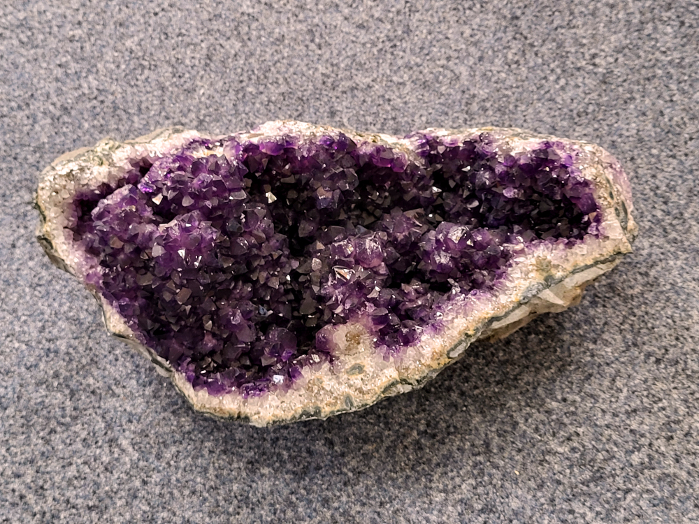 Amethist Cluster Geode, 11,85 kg, 675,- euro, nr. 7
Waar komt amethist vandaan en hoe ontstaan ze?
Amethist wordt wereldwijd gevonden maar de grootste
vondsten worden gedaan in Brazilië, Uruguay, Mexico en Zambia.
Deze edelsteen komt voor in basalt holtes of geodes die ontstaan zijn door
vulkaanuitbarstingen, het duurt miljoenen jaren voordat de kristallen zich vormen.
De kleur van de amethist wordt veroorzaakt door de aanwezigheid
van ijzer en mangaan. 
Waar kan amethist niet goed tegen?
Amethist kan niet goed tegen fel zonlicht en plotselinge
temperatuurwisselingen. Langdurige blootstelling aan zonlicht
doet de kleur doen vervagen en abrupte temperatuur veranderingen
kan voor barsten en/of scheuren zorgen. Amethist kan daarentegen
wel grotendeels tegen water.
Spirituele werking van de amethist:
> Rust, spirituele groei en bescherming.
Amethist staat vooral bekend om zijn kalmerende werking.

                                                                                        -  Kunstgalerie Arnold  - 