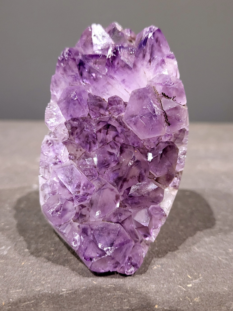 Amethist druzy-0,3 kg, 14,- euro, nr. 11

Beschrijving Amethist.
Amethist is een paarse variëteit van kwarts, bekend om zijn kalmerende en spirituele eigenschappen. De kleur varieert van licht lila tot diep violet en wordt veroorzaakt door sporen van ijzer en andere elementen. Amethist wordt al eeuwenlang gewaardeerd, zowel vanwege zijn esthetische schoonheid als zijn vermeende genezende en beschermende krachten. 
Amethist is een kwartskristal, vaak te vinden in geodes (holtes in gesteente) of als afzonderlijke kristallen. 
De kleur varieert van lichtpaars tot diep violet, soms met roze of blauwe tinten. 
De kleurintensiteit kan variëren, waarbij donkerdere amethisten vaak als kwalitatief worden beschouwd. 
Soms vertoont amethist dichroïsme, waarbij je verschillende kleuren kunt zien wanneer je de steen in het licht draait. 

Vindplaatsen:
Amethist wordt gevonden in verschillende delen van de wereld, waaronder Brazilië, Uruguay, Zambia, Madagaskar, Rusland en Canada.
Het wordt vaak gevonden in bergachtige gebieden. 

Gebruik:
Amethist wordt gebruikt in sieraden, decoratieve objecten en als helende steen. 
Het wordt vaak gedragen als hanger, ring of armband, of geplaatst in ruimtes om de energie te zuiveren. 
Amethist wordt ook gebruikt in meditatie en andere spirituele praktijken. 