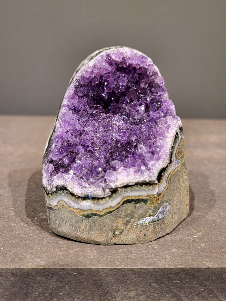 Amethist druzy, 0,4kg, 16,- euro, nr. 12

Beschrijving Amethist.
Amethist is een paarse variëteit van kwarts, bekend om zijn kalmerende en spirituele eigenschappen. De kleur varieert van licht lila tot diep violet en wordt veroorzaakt door sporen van ijzer en andere elementen. Amethist wordt al eeuwenlang gewaardeerd, zowel vanwege zijn esthetische schoonheid als zijn vermeende genezende en beschermende krachten. 
Amethist is een kwartskristal, vaak te vinden in geodes (holtes in gesteente) of als afzonderlijke kristallen. 
De kleur varieert van lichtpaars tot diep violet, soms met roze of blauwe tinten. 
De kleurintensiteit kan variëren, waarbij donkerdere amethisten vaak als kwalitatief worden beschouwd. 
Soms vertoont amethist dichroïsme, waarbij je verschillende kleuren kunt zien wanneer je de steen in het licht draait. 

Vindplaatsen:
Amethist wordt gevonden in verschillende delen van de wereld, waaronder Brazilië, Uruguay, Zambia, Madagaskar, Rusland en Canada.
Het wordt vaak gevonden in bergachtige gebieden. 

Gebruik:
Amethist wordt gebruikt in sieraden, decoratieve objecten en als helende steen. 
Het wordt vaak gedragen als hanger, ring of armband, of geplaatst in ruimtes om de energie te zuiveren. 
Amethist wordt ook gebruikt in meditatie en andere spirituele praktijken.