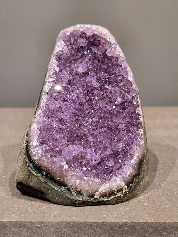 Amethist druzy, 0,5kg, 23,- euro, nr. 16

Beschrijving Amethist.
Amethist is een paarse variëteit van kwarts, bekend om zijn kalmerende en spirituele eigenschappen. De kleur varieert van licht lila tot diep violet en wordt veroorzaakt door sporen van ijzer en andere elementen. Amethist wordt al eeuwenlang gewaardeerd, zowel vanwege zijn esthetische schoonheid als zijn vermeende genezende en beschermende krachten. 
Amethist is een kwartskristal, vaak te vinden in geodes (holtes in gesteente) of als afzonderlijke kristallen. 
De kleur varieert van lichtpaars tot diep violet, soms met roze of blauwe tinten. 
De kleurintensiteit kan variëren, waarbij donkerdere amethisten vaak als kwalitatief worden beschouwd. 
Soms vertoont amethist dichroïsme, waarbij je verschillende kleuren kunt zien wanneer je de steen in het licht draait. 

Vindplaatsen:
Amethist wordt gevonden in verschillende delen van de wereld, waaronder Brazilië, Uruguay, Zambia, Madagaskar, Rusland en Canada.
Het wordt vaak gevonden in bergachtige gebieden. 

Gebruik:
Amethist wordt gebruikt in sieraden, decoratieve objecten en als helende steen. 
Het wordt vaak gedragen als hanger, ring of armband, of geplaatst in ruimtes om de energie te zuiveren. 
Amethist wordt ook gebruikt in meditatie en andere spirituele praktijken. 