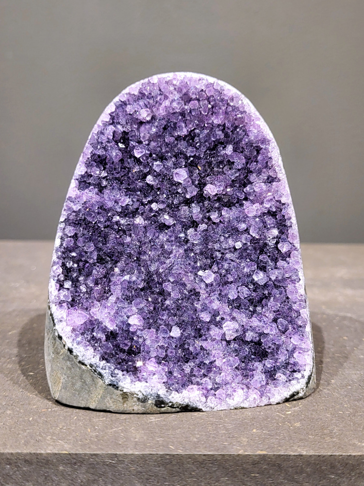 Amethist druzy, 0,5kg, 23,- euro, nr.15

Beschrijving Amethist.
Amethist is een paarse variëteit van kwarts, bekend om zijn kalmerende en spirituele eigenschappen. De kleur varieert van licht lila tot diep violet en wordt veroorzaakt door sporen van ijzer en andere elementen. Amethist wordt al eeuwenlang gewaardeerd, zowel vanwege zijn esthetische schoonheid als zijn vermeende genezende en beschermende krachten. 
Amethist is een kwartskristal, vaak te vinden in geodes (holtes in gesteente) of als afzonderlijke kristallen. 
De kleur varieert van lichtpaars tot diep violet, soms met roze of blauwe tinten. 
De kleurintensiteit kan variëren, waarbij donkerdere amethisten vaak als kwalitatief worden beschouwd. 
Soms vertoont amethist dichroïsme, waarbij je verschillende kleuren kunt zien wanneer je de steen in het licht draait. 

Vindplaatsen:
Amethist wordt gevonden in verschillende delen van de wereld, waaronder Brazilië, Uruguay, Zambia, Madagaskar, Rusland en Canada.
Het wordt vaak gevonden in bergachtige gebieden. 

Gebruik:
Amethist wordt gebruikt in sieraden, decoratieve objecten en als helende steen. 
Het wordt vaak gedragen als hanger, ring of armband, of geplaatst in ruimtes om de energie te zuiveren. 
Amethist wordt ook gebruikt in meditatie en andere spirituele praktijken. 