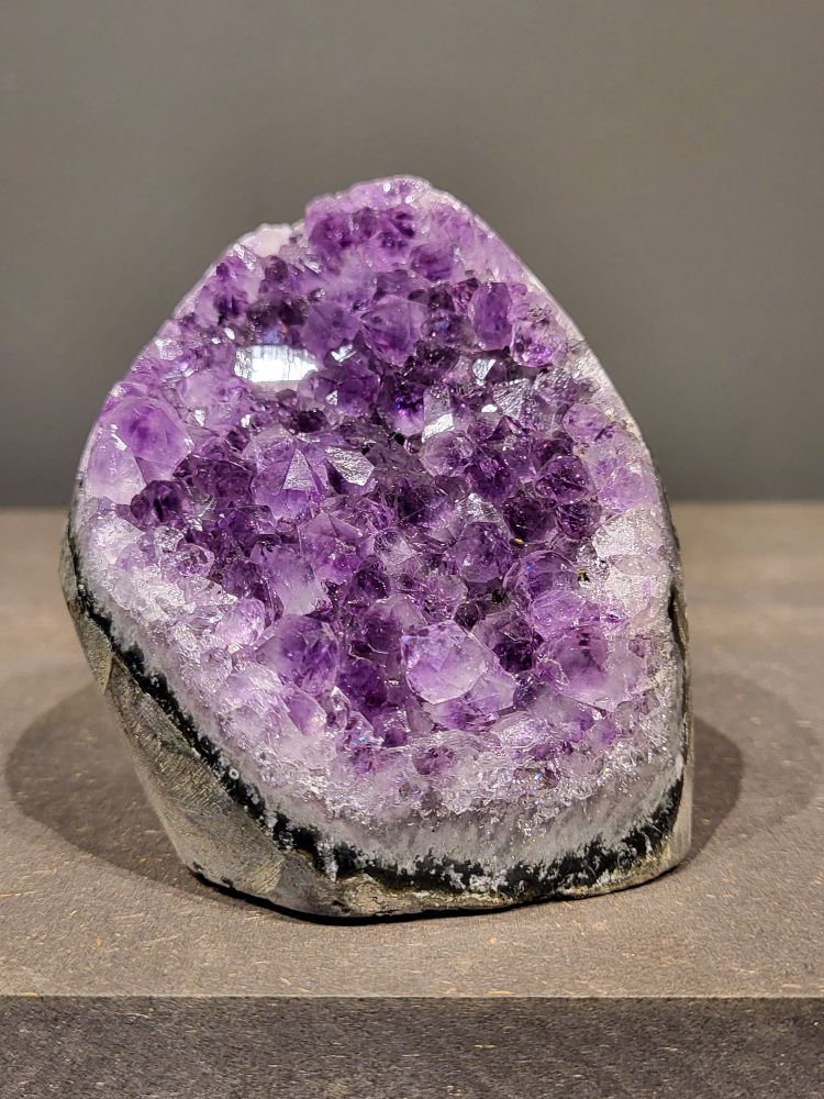 Amethist druzy, 0,6kg, 25,- euro, nr. 17

Beschrijving Amethist.
Amethist is een paarse variëteit van kwarts, bekend om zijn kalmerende en spirituele eigenschappen. De kleur varieert van licht lila tot diep violet en wordt veroorzaakt door sporen van ijzer en andere elementen. Amethist wordt al eeuwenlang gewaardeerd, zowel vanwege zijn esthetische schoonheid als zijn vermeende genezende en beschermende krachten. 
Amethist is een kwartskristal, vaak te vinden in geodes (holtes in gesteente) of als afzonderlijke kristallen. 
De kleur varieert van lichtpaars tot diep violet, soms met roze of blauwe tinten. 
De kleurintensiteit kan variëren, waarbij donkerdere amethisten vaak als kwalitatief worden beschouwd. 
Soms vertoont amethist dichroïsme, waarbij je verschillende kleuren kunt zien wanneer je de steen in het licht draait. 

Vindplaatsen:
Amethist wordt gevonden in verschillende delen van de wereld, waaronder Brazilië, Uruguay, Zambia, Madagaskar, Rusland en Canada.
Het wordt vaak gevonden in bergachtige gebieden. 

Gebruik:
Amethist wordt gebruikt in sieraden, decoratieve objecten en als helende steen. 
Het wordt vaak gedragen als hanger, ring of armband, of geplaatst in ruimtes om de energie te zuiveren. 
Amethist wordt ook gebruikt in meditatie en andere spirituele praktijken. 