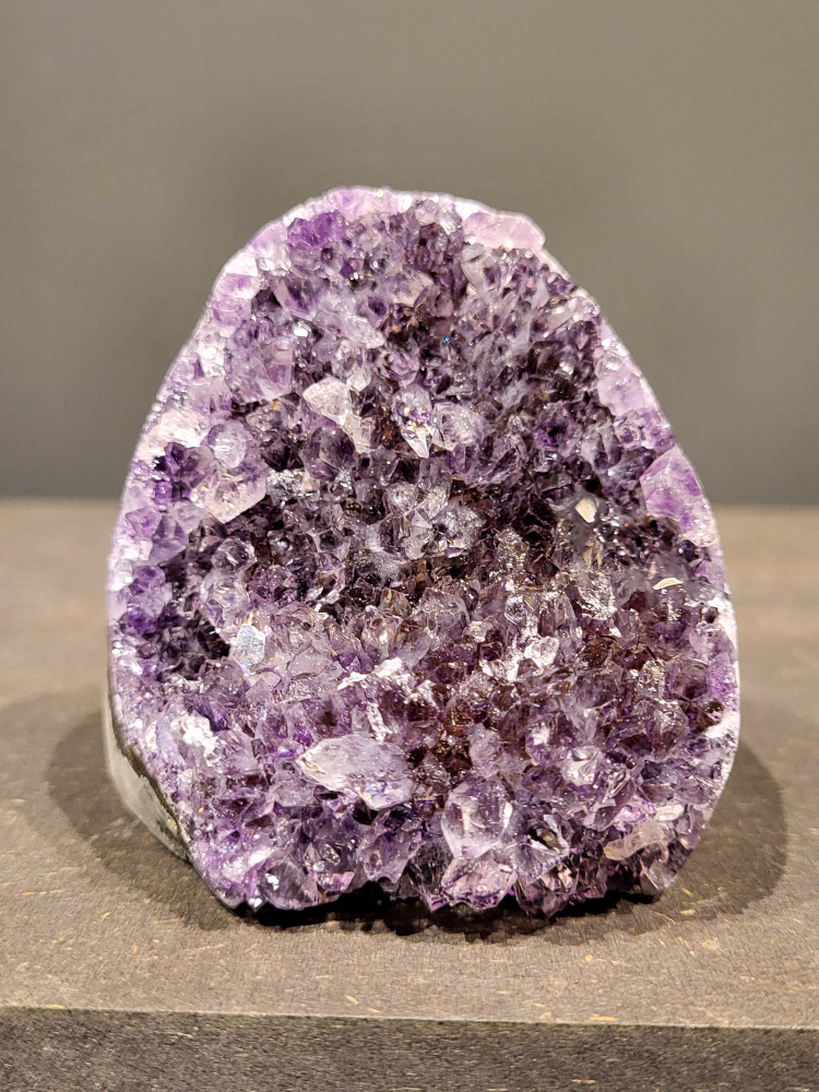 Amethist druzy, 0,8kg, 35,- euro, nr. 32

Beschrijving Amethist.
Amethist is een paarse variëteit van kwarts, bekend om zijn kalmerende en spirituele eigenschappen. De kleur varieert van licht lila tot diep violet en wordt veroorzaakt door sporen van ijzer en andere elementen. Amethist wordt al eeuwenlang gewaardeerd, zowel vanwege zijn esthetische schoonheid als zijn vermeende genezende en beschermende krachten. 
Amethist is een kwartskristal, vaak te vinden in geodes (holtes in gesteente) of als afzonderlijke kristallen. 
De kleur varieert van lichtpaars tot diep violet, soms met roze of blauwe tinten. 
De kleurintensiteit kan variëren, waarbij donkerdere amethisten vaak als kwalitatief worden beschouwd. 
Soms vertoont amethist dichroïsme, waarbij je verschillende kleuren kunt zien wanneer je de steen in het licht draait. 

Vindplaatsen:
Amethist wordt gevonden in verschillende delen van de wereld, waaronder Brazilië, Uruguay, Zambia, Madagaskar, Rusland en Canada.
Het wordt vaak gevonden in bergachtige gebieden. 

Gebruik:
Amethist wordt gebruikt in sieraden, decoratieve objecten en als helende steen. 
Het wordt vaak gedragen als hanger, ring of armband, of geplaatst in ruimtes om de energie te zuiveren. 
Amethist wordt ook gebruikt in meditatie en andere spirituele praktijken. 