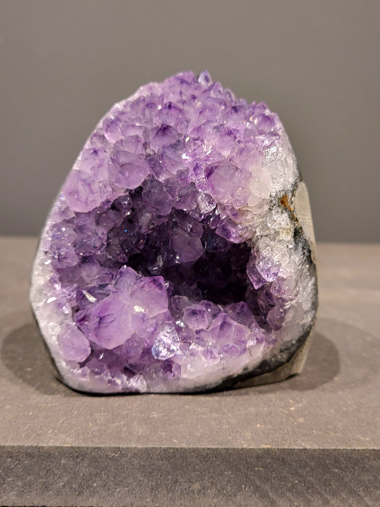 Amethist druzy, 0,8kg, 37,- euro, nr. 31

Beschrijving Amethist.
Amethist is een paarse variëteit van kwarts, bekend om zijn kalmerende en spirituele eigenschappen. De kleur varieert van licht lila tot diep violet en wordt veroorzaakt door sporen van ijzer en andere elementen. Amethist wordt al eeuwenlang gewaardeerd, zowel vanwege zijn esthetische schoonheid als zijn vermeende genezende en beschermende krachten. 
Amethist is een kwartskristal, vaak te vinden in geodes (holtes in gesteente) of als afzonderlijke kristallen. 
De kleur varieert van lichtpaars tot diep violet, soms met roze of blauwe tinten. 
De kleurintensiteit kan variëren, waarbij donkerdere amethisten vaak als kwalitatief worden beschouwd. 
Soms vertoont amethist dichroïsme, waarbij je verschillende kleuren kunt zien wanneer je de steen in het licht draait. 

Vindplaatsen:
Amethist wordt gevonden in verschillende delen van de wereld, waaronder Brazilië, Uruguay, Zambia, Madagaskar, Rusland en Canada.
Het wordt vaak gevonden in bergachtige gebieden. 

Gebruik:
Amethist wordt gebruikt in sieraden, decoratieve objecten en als helende steen. 
Het wordt vaak gedragen als hanger, ring of armband, of geplaatst in ruimtes om de energie te zuiveren. 
Amethist wordt ook gebruikt in meditatie en andere spirituele praktijken. 