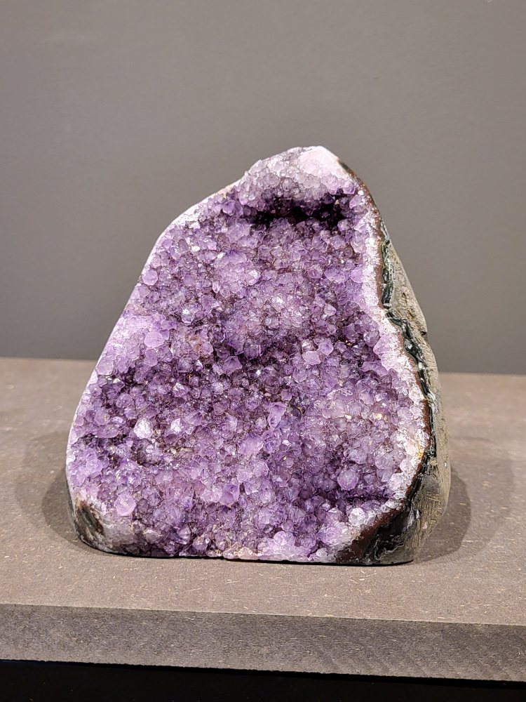 Amethist druzy, 1,5kg, 66,- euro, nr. 34

Beschrijving Amethist.
Amethist is een paarse variëteit van kwarts, bekend om zijn kalmerende en spirituele eigenschappen. De kleur varieert van licht lila tot diep violet en wordt veroorzaakt door sporen van ijzer en andere elementen. Amethist wordt al eeuwenlang gewaardeerd, zowel vanwege zijn esthetische schoonheid als zijn vermeende genezende en beschermende krachten. 
Amethist is een kwartskristal, vaak te vinden in geodes (holtes in gesteente) of als afzonderlijke kristallen. 
De kleur varieert van lichtpaars tot diep violet, soms met roze of blauwe tinten. 
De kleurintensiteit kan variëren, waarbij donkerdere amethisten vaak als kwalitatief worden beschouwd. 
Soms vertoont amethist dichroïsme, waarbij je verschillende kleuren kunt zien wanneer je de steen in het licht draait. 

Vindplaatsen:
Amethist wordt gevonden in verschillende delen van de wereld, waaronder Brazilië, Uruguay, Zambia, Madagaskar, Rusland en Canada.
Het wordt vaak gevonden in bergachtige gebieden. 

Gebruik:
Amethist wordt gebruikt in sieraden, decoratieve objecten en als helende steen. 
Het wordt vaak gedragen als hanger, ring of armband, of geplaatst in ruimtes om de energie te zuiveren. 
Amethist wordt ook gebruikt in meditatie en andere spirituele praktijken. 