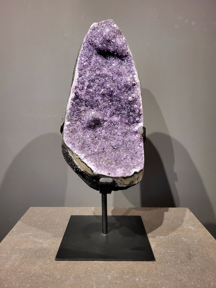 Amethist op standaard, 7,3 kg, 220,- euro, nr. 45

Waar komt amethist vandaan en hoe ontstaan ze?
Amethist wordt wereldwijd gevonden maar de grootste
vondsten worden gedaan in Brazilië, Uruguay, Mexico en Zambia.
Deze edelsteen komt voor in basalt holtes of geodes die ontstaan zijn door
vulkaanuitbarstingen, het duurt miljoenen jaren voordat de kristallen zich vormen.
De kleur van de amethist wordt veroorzaakt door de aanwezigheid
van ijzer en mangaan. 
Waar kan amethist niet goed tegen?
Amethist kan niet goed tegen fel zonlicht en plotselinge
temperatuurwisselingen. Langdurige blootstelling aan zonlicht
doet de kleur doen vervagen en abrupte temperatuur veranderingen
kan voor barsten en/of scheuren zorgen. Amethist kan daarentegen
wel grotendeels tegen water.
Spirituele werking van de amethist:
> Rust, spirituele groei en bescherming.
Amethist staat vooral bekend om zijn kalmerende werking.

                                                                                        -  Kunstgalerie Arnold  - 