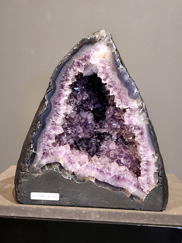 Amethist, 10560 gram, 158,- euro, nr. 19
Waar komt amethist vandaan en hoe ontstaan ze?
Amethist wordt wereldwijd gevonden maar de grootste
vondsten worden gedaan in Brazilië, Uruguay, Mexico en Zambia.
Deze edelsteen komt voor in basalt holtes of geodes die ontstaan zijn door
vulkaanuitbarstingen, het duurt miljoenen jaren voordat de kristallen zich vormen.
De kleur van de amethist wordt veroorzaakt door de aanwezigheid
van ijzer en mangaan. 
Waar kan amethist niet goed tegen?
Amethist kan niet goed tegen fel zonlicht en plotselinge
temperatuurwisselingen. Langdurige blootstelling aan zonlicht
doet de kleur doen vervagen en abrupte temperatuur veranderingen
kan voor barsten en/of scheuren zorgen. Amethist kan daarentegen
wel grotendeels tegen water.
Spirituele werking van de amethist:
> Rust, spirituele groei en bescherming.
Amethist staat vooral bekend om zijn kalmerende werking.

                                                                                        -  Kunstgalerie Arnold  - 