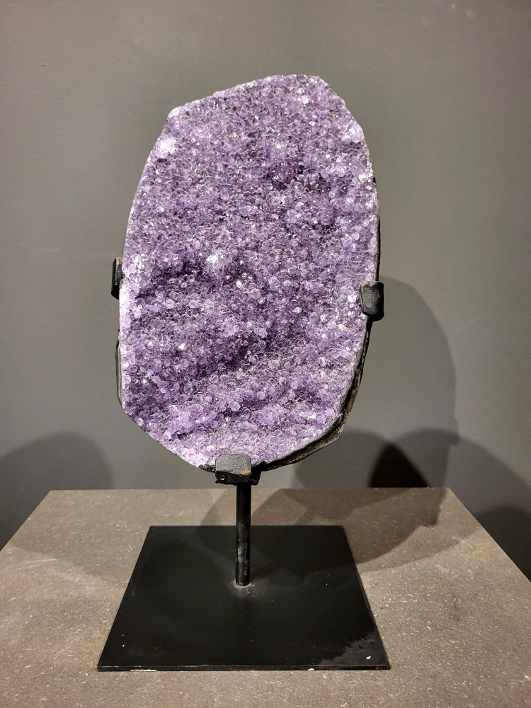 Amethist op standaard, 6,7 kg, 200,- euro, nr. 38

Waar komt amethist vandaan en hoe ontstaan ze?
Amethist wordt wereldwijd gevonden maar de grootste
vondsten worden gedaan in Brazilië, Uruguay, Mexico en Zambia.
Deze edelsteen komt voor in basalt holtes of geodes die ontstaan zijn door
vulkaanuitbarstingen, het duurt miljoenen jaren voordat de kristallen zich vormen.
De kleur van de amethist wordt veroorzaakt door de aanwezigheid
van ijzer en mangaan. 
Waar kan amethist niet goed tegen?
Amethist kan niet goed tegen fel zonlicht en plotselinge
temperatuurwisselingen. Langdurige blootstelling aan zonlicht
doet de kleur doen vervagen en abrupte temperatuur veranderingen
kan voor barsten en/of scheuren zorgen. Amethist kan daarentegen
wel grotendeels tegen water.
Spirituele werking van de amethist:
> Rust, spirituele groei en bescherming.
Amethist staat vooral bekend om zijn kalmerende werking.

                                                                                        -  Kunstgalerie Arnold  -
