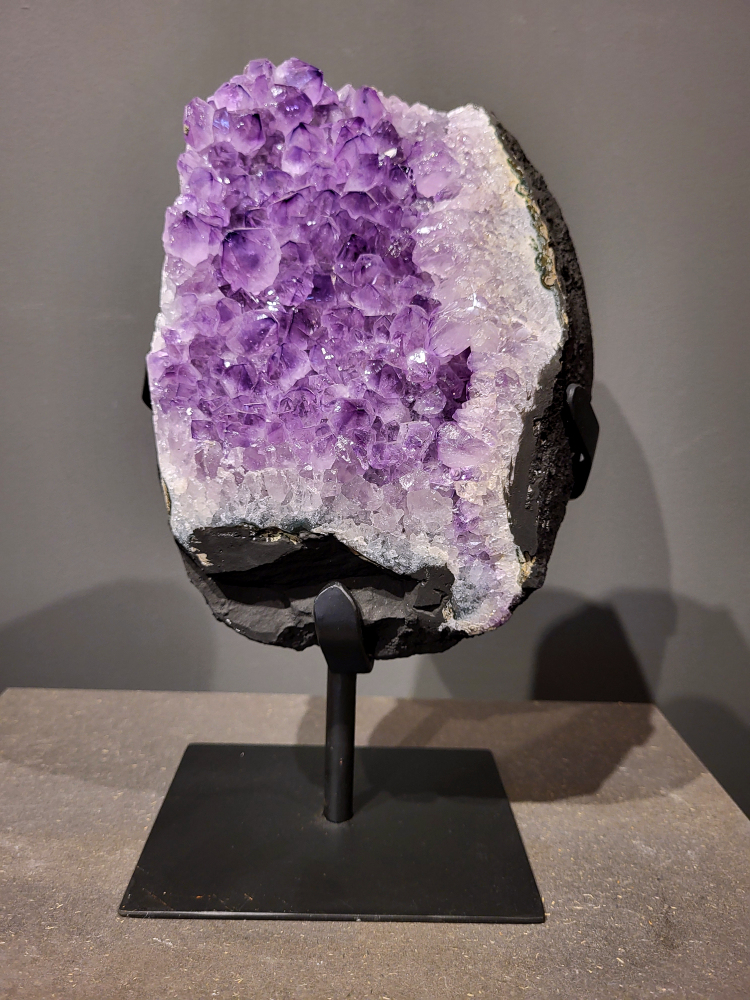 Amethist op standaard, 5,7 kg, 170,- euro, nr. 41

Waar komt amethist vandaan en hoe ontstaan ze?
Amethist wordt wereldwijd gevonden maar de grootste
vondsten worden gedaan in Brazilië, Uruguay, Mexico en Zambia.
Deze edelsteen komt voor in basalt holtes of geodes die ontstaan zijn door
vulkaanuitbarstingen, het duurt miljoenen jaren voordat de kristallen zich vormen.
De kleur van de amethist wordt veroorzaakt door de aanwezigheid
van ijzer en mangaan. 
Waar kan amethist niet goed tegen?
Amethist kan niet goed tegen fel zonlicht en plotselinge
temperatuurwisselingen. Langdurige blootstelling aan zonlicht
doet de kleur doen vervagen en abrupte temperatuur veranderingen
kan voor barsten en/of scheuren zorgen. Amethist kan daarentegen
wel grotendeels tegen water.
Spirituele werking van de amethist:
> Rust, spirituele groei en bescherming.
Amethist staat vooral bekend om zijn kalmerende werking.

                                                                                        -  Kunstgalerie Arnold  - 
