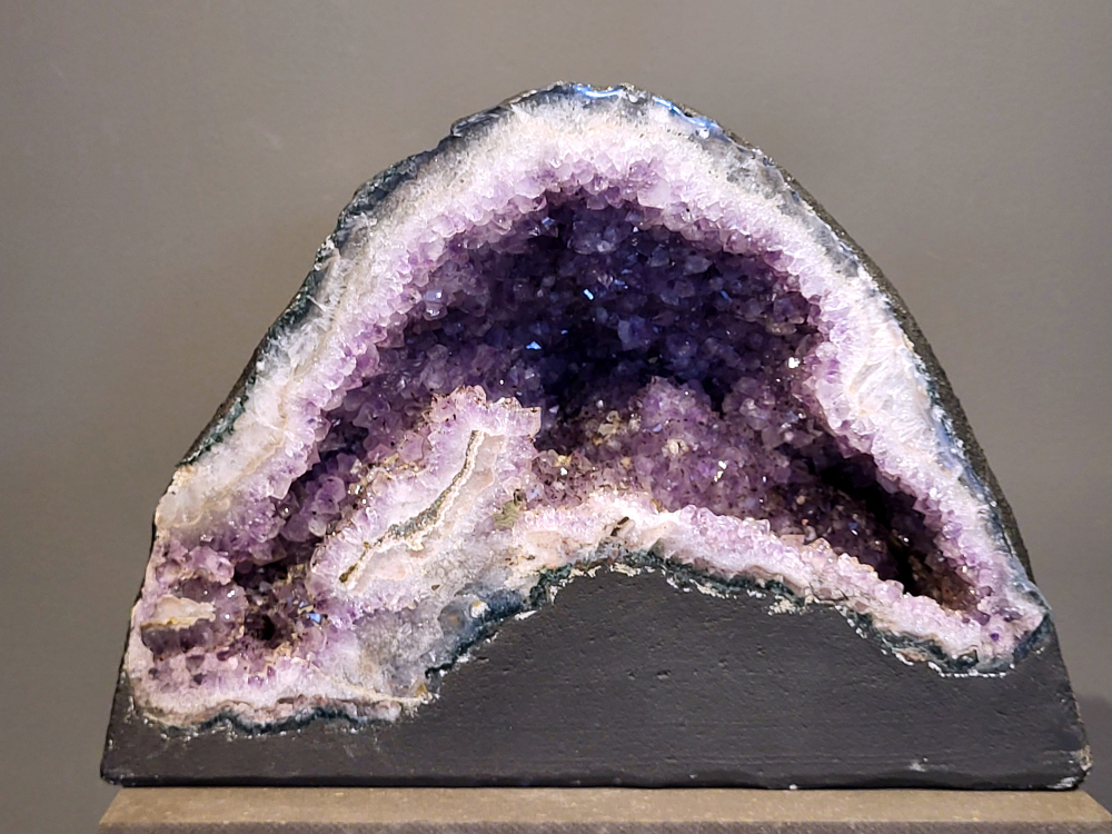 Amethist,  22,36 kg, 295,- euro, nr. 16 
 
Waar komt amethist vandaan en hoe ontstaan ze?
Amethist wordt wereldwijd gevonden maar de grootste
vondsten worden gedaan in Brazilië, Uruguay, Mexico en Zambia.
Deze edelsteen komt voor in basalt holtes of geodes die ontstaan zijn door
vulkaanuitbarstingen, het duurt miljoenen jaren voordat de kristallen zich vormen.
De kleur van de amethist wordt veroorzaakt door de aanwezigheid
van ijzer en mangaan. 
Waar kan amethist niet goed tegen?
Amethist kan niet goed tegen fel zonlicht en plotselinge
temperatuurwisselingen. Langdurige blootstelling aan zonlicht
doet de kleur doen vervagen en abrupte temperatuur veranderingen
kan voor barsten en/of scheuren zorgen. Amethist kan daarentegen
wel grotendeels tegen water.
Spirituele werking van de amethist:
> Rust, spirituele groei en bescherming.
Amethist staat vooral bekend om zijn kalmerende werking.

                                                                                        -  Kunstgalerie Arnold  - 