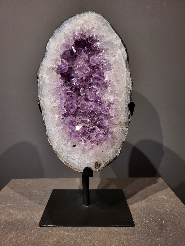 Amethist op standaard, 6 kg, 180,- euro, nr. 42
 
Waar komt amethist vandaan en hoe ontstaan ze?
Amethist wordt wereldwijd gevonden maar de grootste
vondsten worden gedaan in Brazilië, Uruguay, Mexico en Zambia.
Deze edelsteen komt voor in basalt holtes of geodes die ontstaan zijn door
vulkaanuitbarstingen, het duurt miljoenen jaren voordat de kristallen zich vormen.
De kleur van de amethist wordt veroorzaakt door de aanwezigheid
van ijzer en mangaan. 
Waar kan amethist niet goed tegen?
Amethist kan niet goed tegen fel zonlicht en plotselinge
temperatuurwisselingen. Langdurige blootstelling aan zonlicht
doet de kleur doen vervagen en abrupte temperatuur veranderingen
kan voor barsten en/of scheuren zorgen. Amethist kan daarentegen
wel grotendeels tegen water.
Spirituele werking van de amethist:
> Rust, spirituele groei en bescherming.
Amethist staat vooral bekend om zijn kalmerende werking.

                                                                                        -  Kunstgalerie Arnold  - 