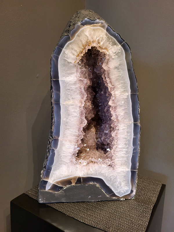 Amethist, 25kg, hoogte 47cm, 295,- euro, nr. 20
Waar komt amethist vandaan en hoe ontstaan ze?
Amethist wordt wereldwijd gevonden maar de grootste
vondsten worden gedaan in Brazilië, Uruguay, Mexico en Zambia.
Deze edelsteen komt voor in basalt holtes of geodes die ontstaan zijn door
vulkaanuitbarstingen, het duurt miljoenen jaren voordat de kristallen zich vormen.
De kleur van de amethist wordt veroorzaakt door de aanwezigheid
van ijzer en mangaan. 
Waar kan amethist niet goed tegen?
Amethist kan niet goed tegen fel zonlicht en plotselinge
temperatuurwisselingen. Langdurige blootstelling aan zonlicht
doet de kleur doen vervagen en abrupte temperatuur veranderingen
kan voor barsten en/of scheuren zorgen. Amethist kan daarentegen
wel grotendeels tegen water.
Spirituele werking van de amethist:
> Rust, spirituele groei en bescherming.
Amethist staat vooral bekend om zijn kalmerende werking.

                                                                                        -  Kunstgalerie Arnold  - 