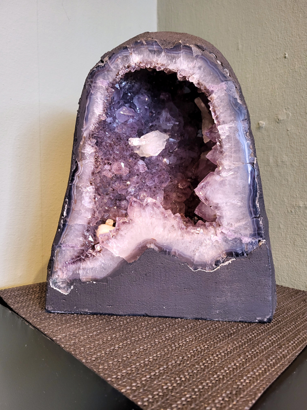 Amethist, 11,72 kg, 28 cm hoog, 165,- euro, nr. 23

Waar komt amethist vandaan en hoe ontstaan ze?
Amethist wordt wereldwijd gevonden maar de grootste
vondsten worden gedaan in Brazilië, Uruguay, Mexico en Zambia.
Deze edelsteen komt voor in basalt holtes of geodes die ontstaan zijn door
vulkaanuitbarstingen, het duurt miljoenen jaren voordat de kristallen zich vormen.
De kleur van de amethist wordt veroorzaakt door de aanwezigheid
van ijzer en mangaan. 
Waar kan amethist niet goed tegen?
Amethist kan niet goed tegen fel zonlicht en plotselinge
temperatuurwisselingen. Langdurige blootstelling aan zonlicht
doet de kleur doen vervagen en abrupte temperatuur veranderingen
kan voor barsten en/of scheuren zorgen. Amethist kan daarentegen
wel grotendeels tegen water.
Spirituele werking van de amethist:
> Rust, spirituele groei en bescherming.
Amethist staat vooral bekend om zijn kalmerende werking.

                                                                                        -  Kunstgalerie Arnold  -