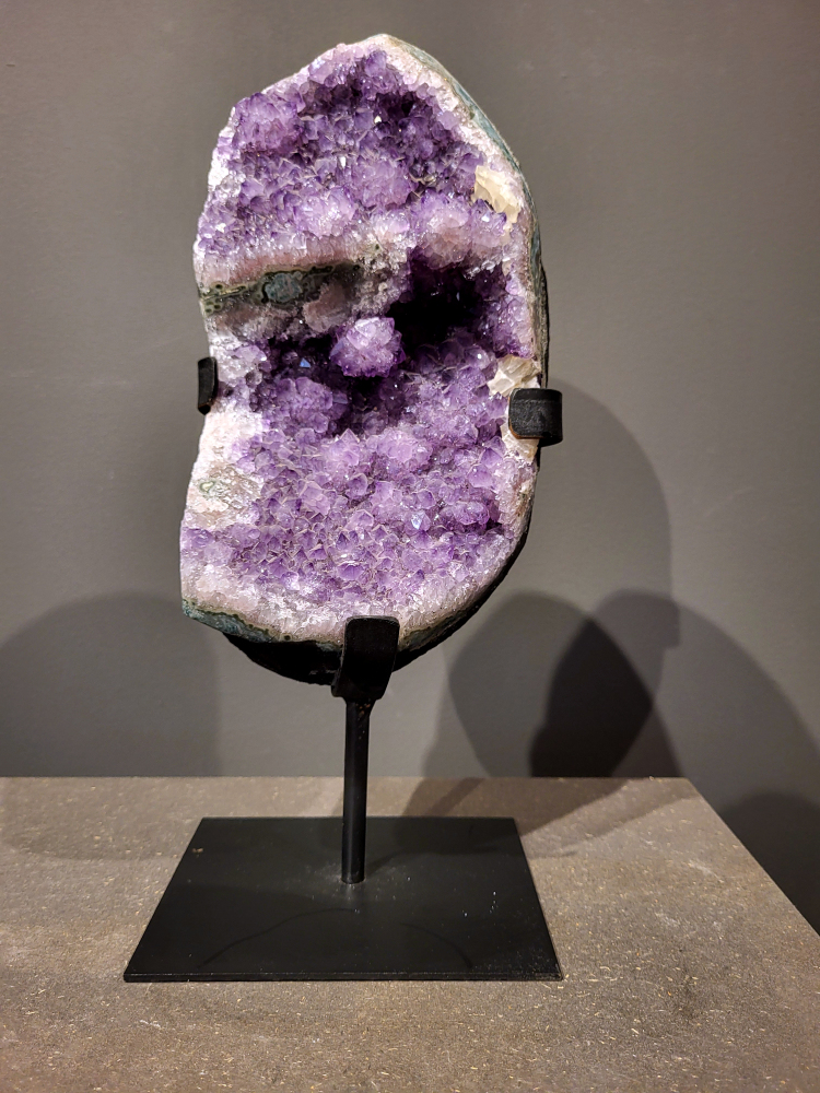 Amethist op standaard, 5,5 kg, 165,- euro, nr. 36

Waar komt amethist vandaan en hoe ontstaan ze?
Amethist wordt wereldwijd gevonden maar de grootste
vondsten worden gedaan in Brazilië, Uruguay, Mexico en Zambia.
Deze edelsteen komt voor in basalt holtes of geodes die ontstaan zijn door
vulkaanuitbarstingen, het duurt miljoenen jaren voordat de kristallen zich vormen.
De kleur van de amethist wordt veroorzaakt door de aanwezigheid
van ijzer en mangaan. 
Waar kan amethist niet goed tegen?
Amethist kan niet goed tegen fel zonlicht en plotselinge
temperatuurwisselingen. Langdurige blootstelling aan zonlicht
doet de kleur doen vervagen en abrupte temperatuur veranderingen
kan voor barsten en/of scheuren zorgen. Amethist kan daarentegen
wel grotendeels tegen water.
Spirituele werking van de amethist:
> Rust, spirituele groei en bescherming.
Amethist staat vooral bekend om zijn kalmerende werking.

                                                                                        -  Kunstgalerie Arnold  - 