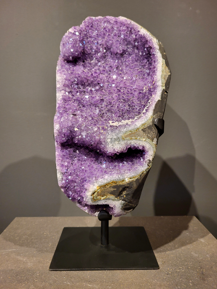 Amethist op standaard, 6,8 kg, hoogte 37cm, 205,- euro, nr.3

Waar komt amethist vandaan en hoe ontstaan ze?
Amethist wordt wereldwijd gevonden maar de grootste
vondsten worden gedaan in Brazilië, Uruguay, Mexico en Zambia.
Deze edelsteen komt voor in basalt holtes of geodes die ontstaan zijn door
vulkaanuitbarstingen, het duurt miljoenen jaren voordat de kristallen zich vormen.
De kleur van de amethist wordt veroorzaakt door de aanwezigheid
van ijzer en mangaan. 
Waar kan amethist niet goed tegen?
Amethist kan niet goed tegen fel zonlicht en plotselinge
temperatuurwisselingen. Langdurige blootstelling aan zonlicht
doet de kleur doen vervagen en abrupte temperatuur veranderingen
kan voor barsten en/of scheuren zorgen. Amethist kan daarentegen
wel grotendeels tegen water.
Spirituele werking van de amethist:
> Rust, spirituele groei en bescherming.
Amethist staat vooral bekend om zijn kalmerende werking.

                                                                                        -  Kunstgalerie Arnold  -