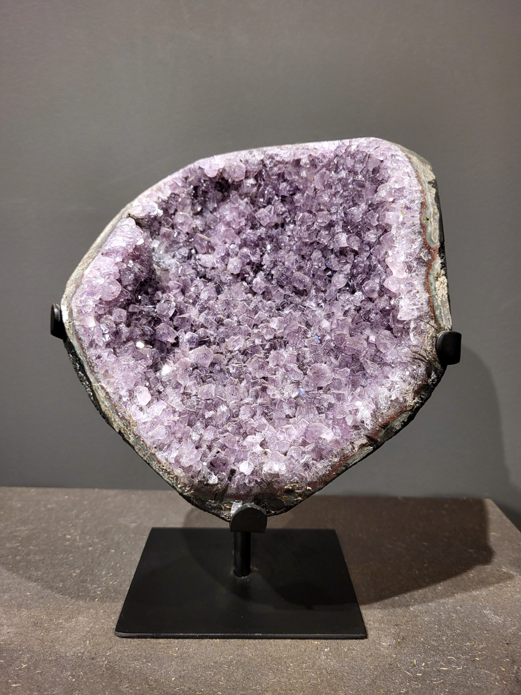 Amethist op standaard, 3,4 kg, 100,- euro, nr. 27
Waar komt amethist vandaan en hoe ontstaan ze?
Amethist wordt wereldwijd gevonden maar de grootste
vondsten worden gedaan in Brazilië, Uruguay, Mexico en Zambia.
Deze edelsteen komt voor in basalt holtes of geodes die ontstaan zijn door
vulkaanuitbarstingen, het duurt miljoenen jaren voordat de kristallen zich vormen.
De kleur van de amethist wordt veroorzaakt door de aanwezigheid
van ijzer en mangaan. 
Waar kan amethist niet goed tegen?
Amethist kan niet goed tegen fel zonlicht en plotselinge
temperatuurwisselingen. Langdurige blootstelling aan zonlicht
doet de kleur doen vervagen en abrupte temperatuur veranderingen
kan voor barsten en/of scheuren zorgen. Amethist kan daarentegen
wel grotendeels tegen water.
Spirituele werking van de amethist:
> Rust, spirituele groei en bescherming.
Amethist staat vooral bekend om zijn kalmerende werking.

                                                                                        -  Kunstgalerie Arnold  - 