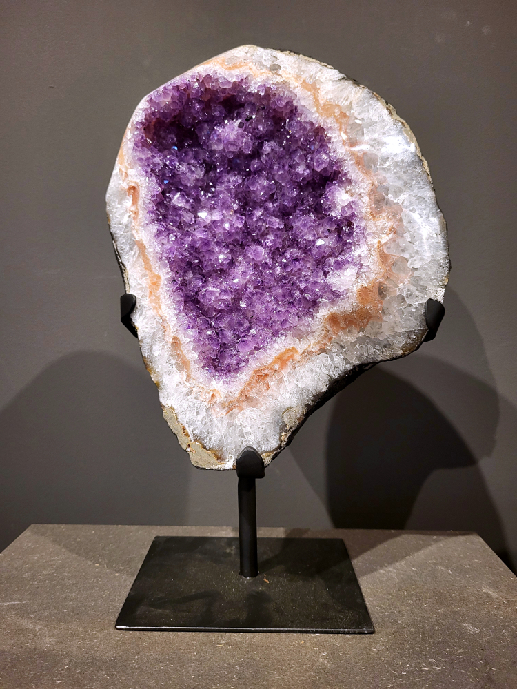Amethist op standaard, 7,2 kg, hoogte 38cm, 215,- euro, nr. 5
 
Waar komt amethist vandaan en hoe ontstaan ze?
Amethist wordt wereldwijd gevonden maar de grootste
vondsten worden gedaan in Brazilië, Uruguay, Mexico en Zambia.
Deze edelsteen komt voor in basalt holtes of geodes die ontstaan zijn door
vulkaanuitbarstingen, het duurt miljoenen jaren voordat de kristallen zich vormen.
De kleur van de amethist wordt veroorzaakt door de aanwezigheid
van ijzer en mangaan. 
Waar kan amethist niet goed tegen?
Amethist kan niet goed tegen fel zonlicht en plotselinge
temperatuurwisselingen. Langdurige blootstelling aan zonlicht
doet de kleur doen vervagen en abrupte temperatuur veranderingen
kan voor barsten en/of scheuren zorgen. Amethist kan daarentegen
wel grotendeels tegen water.
Spirituele werking van de amethist:
> Rust, spirituele groei en bescherming.
Amethist staat vooral bekend om zijn kalmerende werking.

                                                                                        -  Kunstgalerie Arnold  - 