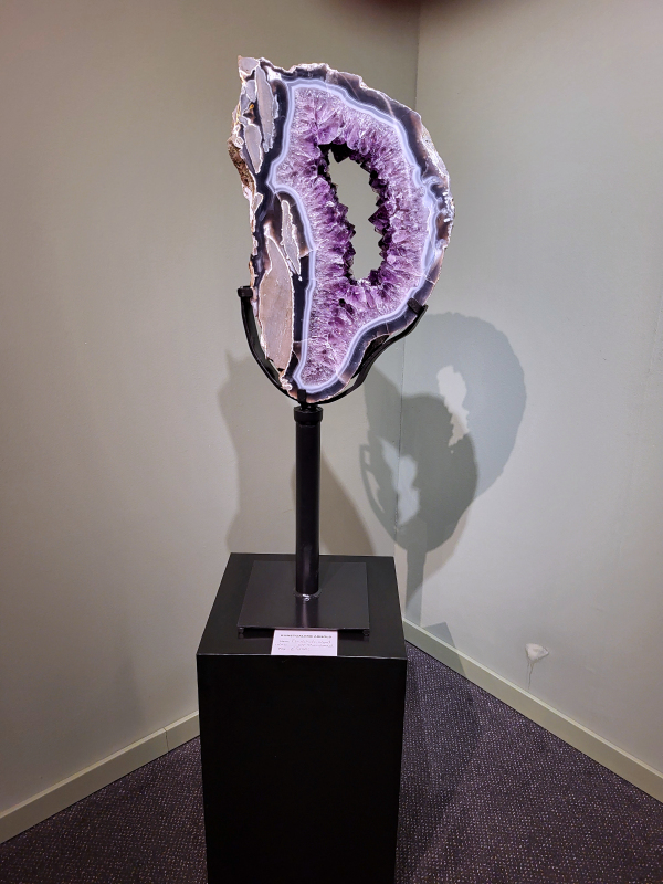 Amethist op standaard, 12kg, hoogte 80cm, 850,- euro, nr. 1.
Waar komt amethist vandaan en hoe ontstaan ze?
Amethist wordt wereldwijd gevonden maar de grootste
vondsten worden gedaan in Brazilië, Uruguay, Mexico en Zambia.
Deze edelsteen komt voor in basalt holtes of geodes die ontstaan zijn door
vulkaanuitbarstingen, het duurt miljoenen jaren voordat de kristallen zich vormen.
De kleur van de amethist wordt veroorzaakt door de aanwezigheid
van ijzer en mangaan. 
Waar kan amethist niet goed tegen?
Amethist kan niet goed tegen fel zonlicht en plotselinge
temperatuurwisselingen. Langdurige blootstelling aan zonlicht
doet de kleur doen vervagen en abrupte temperatuur veranderingen
kan voor barsten en/of scheuren zorgen. Amethist kan daarentegen
wel grotendeels tegen water.
Spirituele werking van de amethist:
> Rust, spirituele groei en bescherming.
Amethist staat vooral bekend om zijn kalmerende werking.

                                                                                        -  Kunstgalerie Arnold  - 