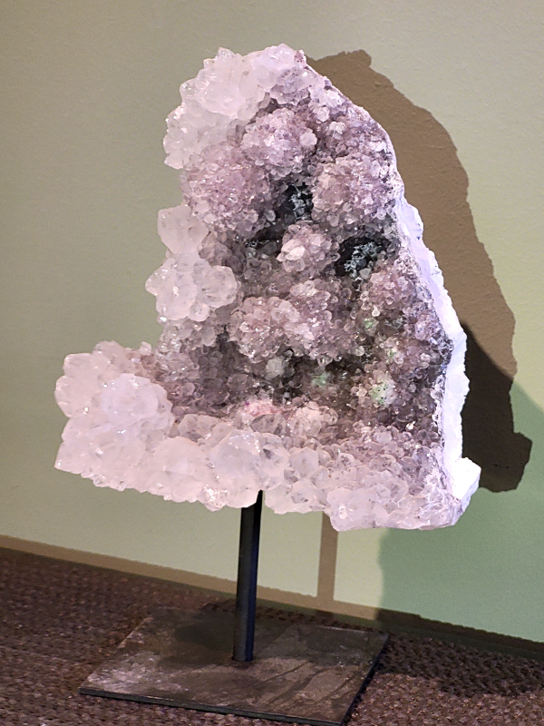 Amethist Roos op standaard, hoogte 22cm incl. standaard, 40,- euro, nr. 47
Waar komt amethist vandaan en hoe ontstaan ze?
Amethist wordt wereldwijd gevonden maar de grootste
vondsten worden gedaan in Brazilië, Uruguay, Mexico en Zambia.
Deze edelsteen komt voor in basalt holtes of geodes die ontstaan zijn door
vulkaanuitbarstingen, het duurt miljoenen jaren voordat de kristallen zich vormen.
De kleur van de amethist wordt veroorzaakt door de aanwezigheid
van ijzer en mangaan. 
Waar kan amethist niet goed tegen?
Amethist kan niet goed tegen fel zonlicht en plotselinge
temperatuurwisselingen. Langdurige blootstelling aan zonlicht
doet de kleur doen vervagen en abrupte temperatuur veranderingen
kan voor barsten en/of scheuren zorgen. Amethist kan daarentegen
wel grotendeels tegen water.
Spirituele werking van de amethist:
> Rust, spirituele groei en bescherming.
Amethist staat vooral bekend om zijn kalmerende werking.

                                                                                        -  Kunstgalerie Arnold  - 