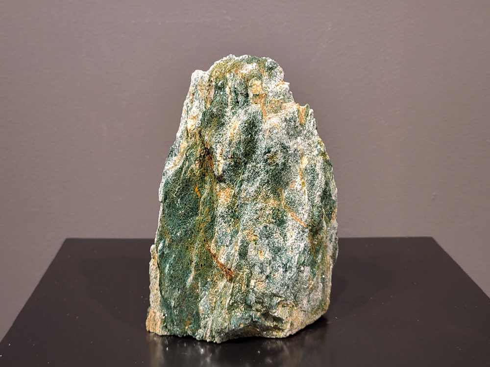 Fuchsiet, 1,7 kg., 17cm hg. en 13cm br., 27,50 euro, nr. 13
Beschrijving, Fuchsiet.

Fuchsiet is een groene, chroomhoudende variant van muscoviet, een soort mica. Het dankt zijn kleur aan de aanwezigheid van chroom en wordt vaak gevonden in metamorf gesteente zoals gneis en schist, maar ook in stollingsgesteente zoals graniet. Fuchsiet wordt beschouwd als een steen die inzicht, zelfbeschikking en bescherming bevordert. 
Eigenschappen en werking:
Inzicht en zelfbeschikking:
Fuchsiet helpt bij het verkrijgen van inzicht in relaties en bevordert een gezonde interactie met anderen, zonder wederzijdse afhankelijkheid. 
Bescherming:
De steen beschermt tegen negatieve energieën en emoties van anderen en helpt je om je grenzen duidelijker te stellen. 
Emotionele balans:
Fuchsiet kan helpen bij het loslaten van negatieve emoties en het overwinnen van een slachtofferrol. 
Fysieke ondersteuning:
Sommige bronnen beweren dat fuchsiet ondersteunend kan werken bij allergieën, jeuk, ontstekingen, bloed- en zenuwklachten. 
Combinaties:
Fuchsiet wordt vaak gevonden met robijn, waarbij de combinatie krachtige energie, moed en doorzettingsvermogen kan versterken. 
Chakra:
Fuchsiet wordt geassocieerd met het hartchakra (4e chakra). 
Verzorging:
Fuchsiet kan beter niet met water gereinigd worden, aldus Edelstenen en Mineralen. 
Andere bronnen suggereren dat het reinigen onder stromend water of een nacht in zout water een optie is. 
Vindplaatsen:
Brazilië is een bekende vindplaats van fuchsiet.