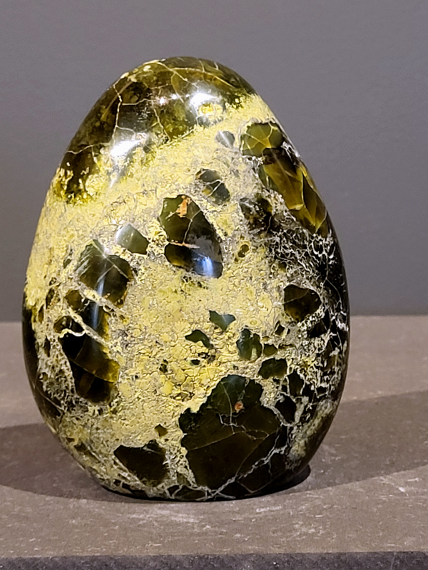 Groene Opaal – Edelsteen van rust en vernieuwing
Chakra: het hartchakra (4e chakra)

Wat is groene opaal?
Groene opaal is een edelsteen met een frisse, levendige kleur die vaak blauwgroen tot lichtgroen glanst. De steen wordt vooral gevonden in Australië, Peru en Mexico. Groene opaal ontstaat, net als andere opaalsoorten, door de afzetting van siliciumdioxide (SiO₂) en water in spleten en holtes van gesteente.
De groene kleur komt meestal door kleine sporen van mineralen zoals nikkel en koper, of door insluitsels van andere mineralen.

Werking en betekenis van groene opaal.
Groene opaal staat bekend om zijn kalmerende en helende werking. Veel mensen gebruiken de steen om:
emotioneel herstel te ondersteunen,
meer zelfliefde te ervaren,
oude pijn los te laten,
relaties te versterken,
creativiteit te stimuleren,
en een positieve stemming te bevorderen.
Kortom: een steen die rust en vernieuwing brengt.

Waar kan groene opaal niet goed tegen?
Net als andere opalen kan groene opaal niet goed tegen fel zonlicht, water, zeep en parfum. Bewaar de steen dus op een droge plek, uit het directe zonlicht, om hem mooi te houden.

Hoe laad je groene opaal op?
Je kunt groene opaal opladen door hem tijdens volle maan in het maanlicht te leggen. Ook kan dit met een selenietsteen of in een Meru-piramide (een piramidevormig instrument dat gebruikt wordt om energie en vibraties te versterken).

Geïnteresseerd in groene opaal?
Wil je deze bijzondere steen in het echt zien? Neem gerust contact met ons op of bezoek de galerie. Daar vind je onze volledige collectie edelstenen en kunstwerken.