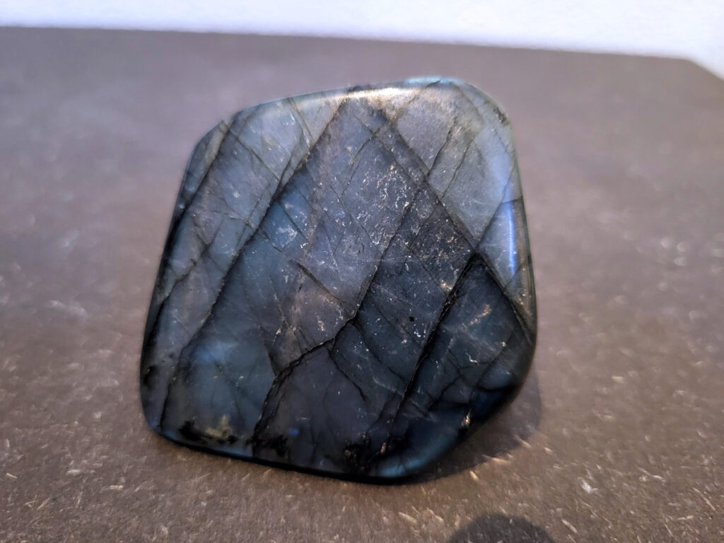 Labradoriet, 0,1kg, 5cm hoog, 6,- euro, nr. 41
Beschrijving, Labradoriet.
Labradoriet is een edelsteen die bekend staat om zijn iriserende kleurenspel, ook wel labradoriseren genoemd, dat vaak doet denken aan het noorderlicht. Het is een populaire steen in de edelstenenwereld vanwege zowel zijn uiterlijk als zijn vermeende spirituele eigenschappen. 
Wat is labradoriet?
Labradoriet is een veldspaatmineraal dat wordt gekenmerkt door een opaalachtig glans of iriserend effect, veroorzaakt door de lichtbreking in de interne structuur van de steen.
De meest voorkomende kleur is grijs of groenachtig grijs, maar de steen kan ook blauwe, gele, oranje, paarse of zelfs rode flitsen laten zien.
De steen is genoemd naar het Canadese schiereiland Labrador, waar het voor het eerst werd ontdekt. 
Spirituele betekenis en eigenschappen:
Labradoriet wordt vaak beschouwd als een beschermende steen, vooral voor mensen die gevoelig zijn voor de energieën van hun omgeving. 
Het zou helpen bij het versterken van de aura en het verminderen van energielekkage, waardoor je je weerbaarder voelt. 
Labradoriet wordt geassocieerd met het versterken van intuïtie, het vergroten van het bewustzijn en het transformeren van negatieve energieën. 
Het wordt ook gebruikt om blokkades op te heffen en de innerlijke wijsheid te onthullen. 
Gebruik:
Labradoriet wordt vaak verwerkt in sieraden zoals hangers, armbanden en oorbellen. 
Het kan ook als ruwe steen, knuffelsteen of in andere vormen worden gebruikt, bijvoorbeeld in een huis of op een werkplek. 
Labradoriet kan worden gereinigd door het onder stromend water te houden of door het te reinigen met een andere steen zoals bergkristal of seleniet. 
Vindplaatsen:
Labradoriet wordt gevonden op verschillende locaties over de hele wereld, waaronder Canada, Finland, Madagaskar en Rusland. 
                                -Kunstgalerie Arnold-