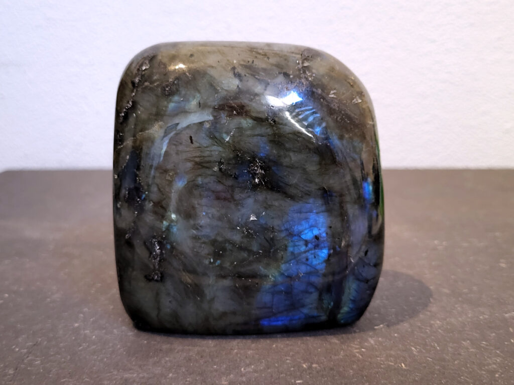 Labradoriet, 0,7kg, 10cm hoog, 22,-euro, nr. 36
Beschrijving, Labradoriet.
Labradoriet is een edelsteen die bekend staat om zijn iriserende kleurenspel, ook wel labradoriseren genoemd, dat vaak doet denken aan het noorderlicht. Het is een populaire steen in de edelstenenwereld vanwege zowel zijn uiterlijk als zijn vermeende spirituele eigenschappen. 
Wat is labradoriet?
Labradoriet is een veldspaatmineraal dat wordt gekenmerkt door een opaalachtig glans of iriserend effect, veroorzaakt door de lichtbreking in de interne structuur van de steen.
De meest voorkomende kleur is grijs of groenachtig grijs, maar de steen kan ook blauwe, gele, oranje, paarse of zelfs rode flitsen laten zien.
De steen is genoemd naar het Canadese schiereiland Labrador, waar het voor het eerst werd ontdekt. 
Spirituele betekenis en eigenschappen:
Labradoriet wordt vaak beschouwd als een beschermende steen, vooral voor mensen die gevoelig zijn voor de energieën van hun omgeving. 
Het zou helpen bij het versterken van de aura en het verminderen van energielekkage, waardoor je je weerbaarder voelt. 
Labradoriet wordt geassocieerd met het versterken van intuïtie, het vergroten van het bewustzijn en het transformeren van negatieve energieën. 
Het wordt ook gebruikt om blokkades op te heffen en de innerlijke wijsheid te onthullen. 
Gebruik:
Labradoriet wordt vaak verwerkt in sieraden zoals hangers, armbanden en oorbellen. 
Het kan ook als ruwe steen, knuffelsteen of in andere vormen worden gebruikt, bijvoorbeeld in een huis of op een werkplek. 
Labradoriet kan worden gereinigd door het onder stromend water te houden of door het te reinigen met een andere steen zoals bergkristal of seleniet. 
Vindplaatsen:
Labradoriet wordt gevonden op verschillende locaties over de hele wereld, waaronder Canada, Finland, Madagaskar en Rusland. 
                                -Kunstgalerie Arnold-