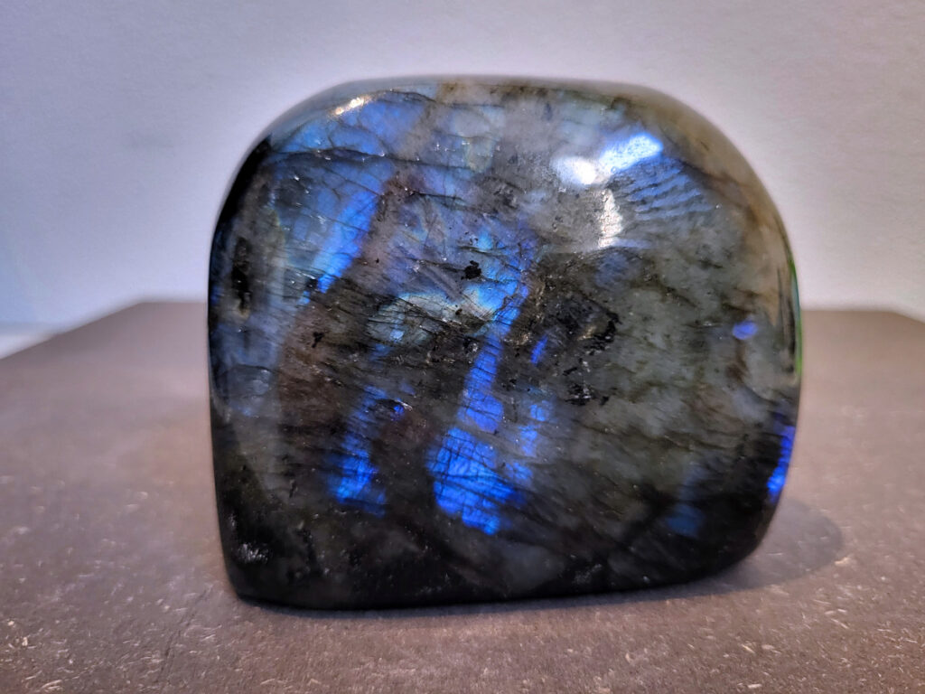 Labradoriet, 0,7kg, 8cm hoog, 22,- euro, nr. 37
Beschrijving, Labradoriet.
Labradoriet is een edelsteen die bekend staat om zijn iriserende kleurenspel, ook wel labradoriseren genoemd, dat vaak doet denken aan het noorderlicht. Het is een populaire steen in de edelstenenwereld vanwege zowel zijn uiterlijk als zijn vermeende spirituele eigenschappen. 
Wat is labradoriet?
Labradoriet is een veldspaatmineraal dat wordt gekenmerkt door een opaalachtig glans of iriserend effect, veroorzaakt door de lichtbreking in de interne structuur van de steen.
De meest voorkomende kleur is grijs of groenachtig grijs, maar de steen kan ook blauwe, gele, oranje, paarse of zelfs rode flitsen laten zien.
De steen is genoemd naar het Canadese schiereiland Labrador, waar het voor het eerst werd ontdekt. 
Spirituele betekenis en eigenschappen:
Labradoriet wordt vaak beschouwd als een beschermende steen, vooral voor mensen die gevoelig zijn voor de energieën van hun omgeving. 
Het zou helpen bij het versterken van de aura en het verminderen van energielekkage, waardoor je je weerbaarder voelt. 
Labradoriet wordt geassocieerd met het versterken van intuïtie, het vergroten van het bewustzijn en het transformeren van negatieve energieën. 
Het wordt ook gebruikt om blokkades op te heffen en de innerlijke wijsheid te onthullen. 
Gebruik:
Labradoriet wordt vaak verwerkt in sieraden zoals hangers, armbanden en oorbellen. 
Het kan ook als ruwe steen, knuffelsteen of in andere vormen worden gebruikt, bijvoorbeeld in een huis of op een werkplek. 
Labradoriet kan worden gereinigd door het onder stromend water te houden of door het te reinigen met een andere steen zoals bergkristal of seleniet. 
Vindplaatsen:
Labradoriet wordt gevonden op verschillende locaties over de hele wereld, waaronder Canada, Finland, Madagaskar en Rusland. 
                                -Kunstgalerie Arnold-