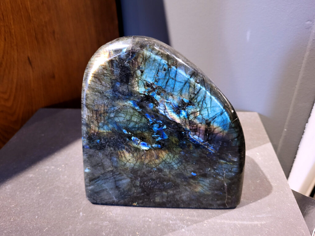 Labradoriet, 3,2kg, 17cm hoog, 114,- euro, nr. 5
Beschrijving, Labradoriet.
Labradoriet is een edelsteen die bekend staat om zijn iriserende kleurenspel, ook wel labradoriseren genoemd, dat vaak doet denken aan het noorderlicht. Het is een populaire steen in de edelstenenwereld vanwege zowel zijn uiterlijk als zijn vermeende spirituele eigenschappen. 
Wat is labradoriet?
Labradoriet is een veldspaatmineraal dat wordt gekenmerkt door een opaalachtig glans of iriserend effect, veroorzaakt door de lichtbreking in de interne structuur van de steen.
De meest voorkomende kleur is grijs of groenachtig grijs, maar de steen kan ook blauwe, gele, oranje, paarse of zelfs rode flitsen laten zien.
De steen is genoemd naar het Canadese schiereiland Labrador, waar het voor het eerst werd ontdekt. 
Spirituele betekenis en eigenschappen:
Labradoriet wordt vaak beschouwd als een beschermende steen, vooral voor mensen die gevoelig zijn voor de energieën van hun omgeving. 
Het zou helpen bij het versterken van de aura en het verminderen van energielekkage, waardoor je je weerbaarder voelt. 
Labradoriet wordt geassocieerd met het versterken van intuïtie, het vergroten van het bewustzijn en het transformeren van negatieve energieën. 
Het wordt ook gebruikt om blokkades op te heffen en de innerlijke wijsheid te onthullen. 
Gebruik:
Labradoriet wordt vaak verwerkt in sieraden zoals hangers, armbanden en oorbellen. 
Het kan ook als ruwe steen, knuffelsteen of in andere vormen worden gebruikt, bijvoorbeeld in een huis of op een werkplek. 
Labradoriet kan worden gereinigd door het onder stromend water te houden of door het te reinigen met een andere steen zoals bergkristal of seleniet. 
Vindplaatsen:
Labradoriet wordt gevonden op verschillende locaties over de hele wereld, waaronder Canada, Finland, Madagaskar en Rusland. 

                       -kunstgalerie-arnold-