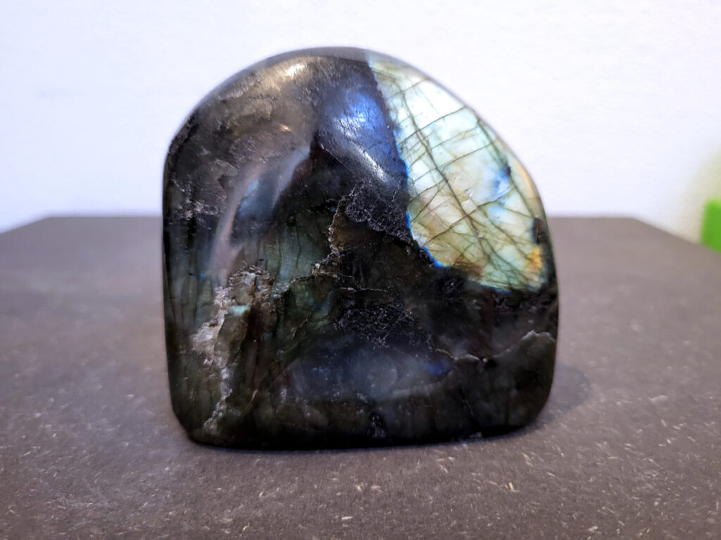 Labradoriet, 0,6kg, 8cm hoog, 17,- euro, nr. 35
Beschrijving, Labradoriet.
Labradoriet is een edelsteen die bekend staat om zijn iriserende kleurenspel, ook wel labradoriseren genoemd, dat vaak doet denken aan het noorderlicht. Het is een populaire steen in de edelstenenwereld vanwege zowel zijn uiterlijk als zijn vermeende spirituele eigenschappen. 
Wat is labradoriet?
Labradoriet is een veldspaatmineraal dat wordt gekenmerkt door een opaalachtig glans of iriserend effect, veroorzaakt door de lichtbreking in de interne structuur van de steen.
De meest voorkomende kleur is grijs of groenachtig grijs, maar de steen kan ook blauwe, gele, oranje, paarse of zelfs rode flitsen laten zien.
De steen is genoemd naar het Canadese schiereiland Labrador, waar het voor het eerst werd ontdekt. 
Spirituele betekenis en eigenschappen:
Labradoriet wordt vaak beschouwd als een beschermende steen, vooral voor mensen die gevoelig zijn voor de energieën van hun omgeving. 
Het zou helpen bij het versterken van de aura en het verminderen van energielekkage, waardoor je je weerbaarder voelt. 
Labradoriet wordt geassocieerd met het versterken van intuïtie, het vergroten van het bewustzijn en het transformeren van negatieve energieën. 
Het wordt ook gebruikt om blokkades op te heffen en de innerlijke wijsheid te onthullen. 
Gebruik:
Labradoriet wordt vaak verwerkt in sieraden zoals hangers, armbanden en oorbellen. 
Het kan ook als ruwe steen, knuffelsteen of in andere vormen worden gebruikt, bijvoorbeeld in een huis of op een werkplek. 
Labradoriet kan worden gereinigd door het onder stromend water te houden of door het te reinigen met een andere steen zoals bergkristal of seleniet. 
Vindplaatsen:
Labradoriet wordt gevonden op verschillende locaties over de hele wereld, waaronder Canada, Finland, Madagaskar en Rusland. 
                                -Kunstgalerie Arnold-