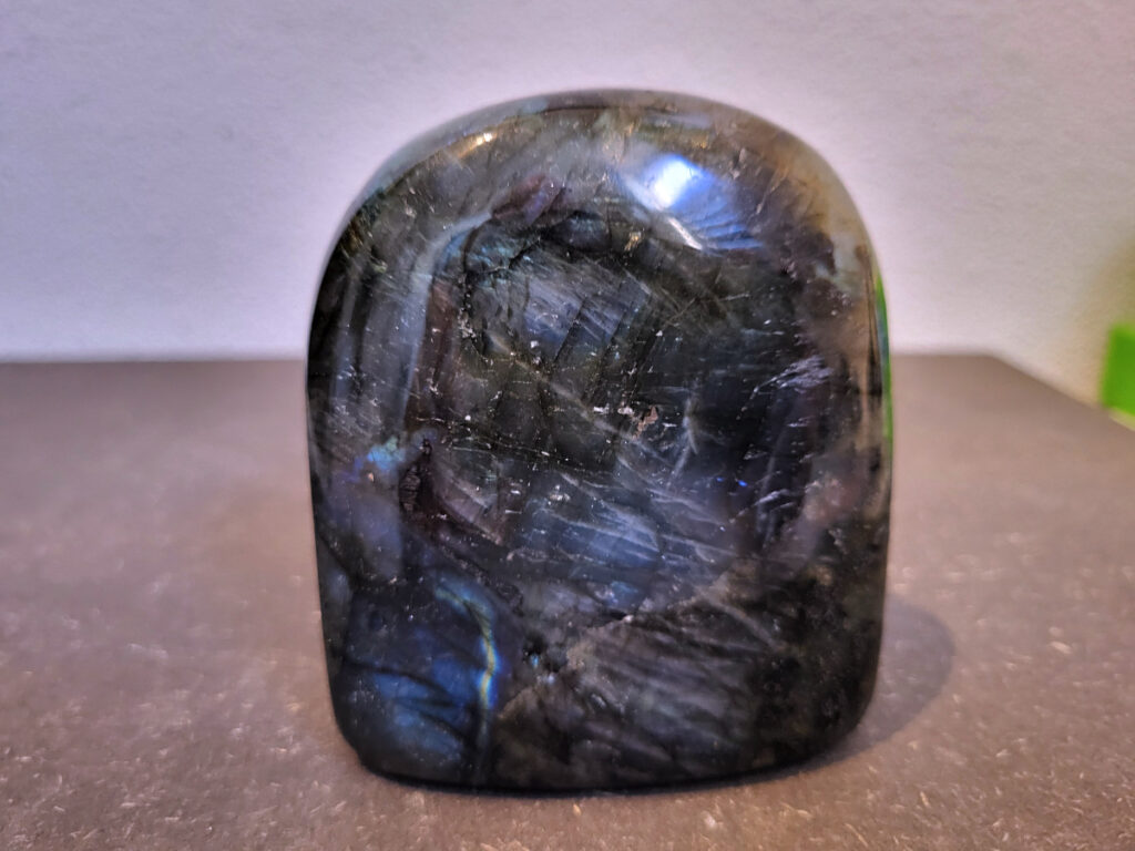 Labradoriet, 0,6kg, 9cm hoog, 17,- euro, nr. 34
Beschrijving, Labradoriet.
Labradoriet is een edelsteen die bekend staat om zijn iriserende kleurenspel, ook wel labradoriseren genoemd, dat vaak doet denken aan het noorderlicht. Het is een populaire steen in de edelstenenwereld vanwege zowel zijn uiterlijk als zijn vermeende spirituele eigenschappen. 
Wat is labradoriet?
Labradoriet is een veldspaatmineraal dat wordt gekenmerkt door een opaalachtig glans of iriserend effect, veroorzaakt door de lichtbreking in de interne structuur van de steen.
De meest voorkomende kleur is grijs of groenachtig grijs, maar de steen kan ook blauwe, gele, oranje, paarse of zelfs rode flitsen laten zien.
De steen is genoemd naar het Canadese schiereiland Labrador, waar het voor het eerst werd ontdekt. 
Spirituele betekenis en eigenschappen:
Labradoriet wordt vaak beschouwd als een beschermende steen, vooral voor mensen die gevoelig zijn voor de energieën van hun omgeving. 
Het zou helpen bij het versterken van de aura en het verminderen van energielekkage, waardoor je je weerbaarder voelt. 
Labradoriet wordt geassocieerd met het versterken van intuïtie, het vergroten van het bewustzijn en het transformeren van negatieve energieën. 
Het wordt ook gebruikt om blokkades op te heffen en de innerlijke wijsheid te onthullen. 
Gebruik:
Labradoriet wordt vaak verwerkt in sieraden zoals hangers, armbanden en oorbellen. 
Het kan ook als ruwe steen, knuffelsteen of in andere vormen worden gebruikt, bijvoorbeeld in een huis of op een werkplek. 
Labradoriet kan worden gereinigd door het onder stromend water te houden of door het te reinigen met een andere steen zoals bergkristal of seleniet. 
Vindplaatsen:
Labradoriet wordt gevonden op verschillende locaties over de hele wereld, waaronder Canada, Finland, Madagaskar en Rusland. 
                                -Kunstgalerie Arnold-