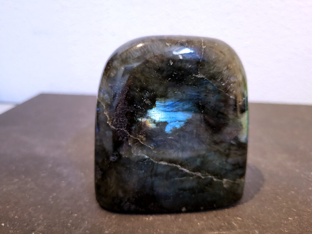 Labradoriet, 0,6kg, 9cm hoog, 17,-euro, nr. 33
Beschrijving, Labradoriet.
Labradoriet is een edelsteen die bekend staat om zijn iriserende kleurenspel, ook wel labradoriseren genoemd, dat vaak doet denken aan het noorderlicht. Het is een populaire steen in de edelstenenwereld vanwege zowel zijn uiterlijk als zijn vermeende spirituele eigenschappen. 
Wat is labradoriet?
Labradoriet is een veldspaatmineraal dat wordt gekenmerkt door een opaalachtig glans of iriserend effect, veroorzaakt door de lichtbreking in de interne structuur van de steen.
De meest voorkomende kleur is grijs of groenachtig grijs, maar de steen kan ook blauwe, gele, oranje, paarse of zelfs rode flitsen laten zien.
De steen is genoemd naar het Canadese schiereiland Labrador, waar het voor het eerst werd ontdekt. 
Spirituele betekenis en eigenschappen:
Labradoriet wordt vaak beschouwd als een beschermende steen, vooral voor mensen die gevoelig zijn voor de energieën van hun omgeving. 
Het zou helpen bij het versterken van de aura en het verminderen van energielekkage, waardoor je je weerbaarder voelt. 
Labradoriet wordt geassocieerd met het versterken van intuïtie, het vergroten van het bewustzijn en het transformeren van negatieve energieën. 
Het wordt ook gebruikt om blokkades op te heffen en de innerlijke wijsheid te onthullen. 
Gebruik:
Labradoriet wordt vaak verwerkt in sieraden zoals hangers, armbanden en oorbellen. 
Het kan ook als ruwe steen, knuffelsteen of in andere vormen worden gebruikt, bijvoorbeeld in een huis of op een werkplek. 
Labradoriet kan worden gereinigd door het onder stromend water te houden of door het te reinigen met een andere steen zoals bergkristal of seleniet. 
Vindplaatsen:
Labradoriet wordt gevonden op verschillende locaties over de hele wereld, waaronder Canada, Finland, Madagaskar en Rusland. 
                                -Kunstgalerie Arnold-