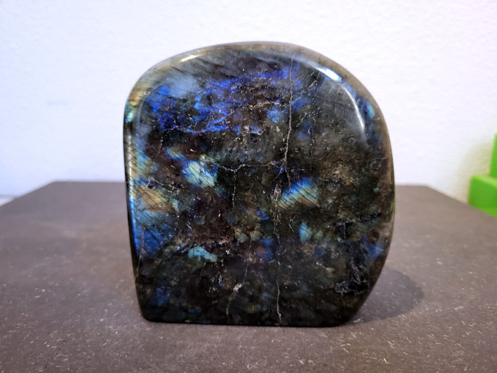 Labradoriet, 0,9kg, 11cm hoog, 28,- euro, nr. 30
Beschrijving, Labradoriet.
Labradoriet is een edelsteen die bekend staat om zijn iriserende kleurenspel, ook wel labradoriseren genoemd, dat vaak doet denken aan het noorderlicht. Het is een populaire steen in de edelstenenwereld vanwege zowel zijn uiterlijk als zijn vermeende spirituele eigenschappen. 
Wat is labradoriet?
Labradoriet is een veldspaatmineraal dat wordt gekenmerkt door een opaalachtig glans of iriserend effect, veroorzaakt door de lichtbreking in de interne structuur van de steen.
De meest voorkomende kleur is grijs of groenachtig grijs, maar de steen kan ook blauwe, gele, oranje, paarse of zelfs rode flitsen laten zien.
De steen is genoemd naar het Canadese schiereiland Labrador, waar het voor het eerst werd ontdekt. 
Spirituele betekenis en eigenschappen:
Labradoriet wordt vaak beschouwd als een beschermende steen, vooral voor mensen die gevoelig zijn voor de energieën van hun omgeving. 
Het zou helpen bij het versterken van de aura en het verminderen van energielekkage, waardoor je je weerbaarder voelt. 
Labradoriet wordt geassocieerd met het versterken van intuïtie, het vergroten van het bewustzijn en het transformeren van negatieve energieën. 
Het wordt ook gebruikt om blokkades op te heffen en de innerlijke wijsheid te onthullen. 
Gebruik:
Labradoriet wordt vaak verwerkt in sieraden zoals hangers, armbanden en oorbellen. 
Het kan ook als ruwe steen, knuffelsteen of in andere vormen worden gebruikt, bijvoorbeeld in een huis of op een werkplek. 
Labradoriet kan worden gereinigd door het onder stromend water te houden of door het te reinigen met een andere steen zoals bergkristal of seleniet. 
Vindplaatsen:
Labradoriet wordt gevonden op verschillende locaties over de hele wereld, waaronder Canada, Finland, Madagaskar en Rusland. 
                                -Kunstgalerie Arnold-