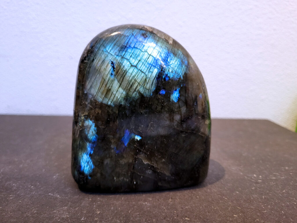 Labradoriet, 0,8kg, 11cm hoog, 23,- euro, nr. 29
Beschrijving, Labradoriet.
Labradoriet is een edelsteen die bekend staat om zijn iriserende kleurenspel, ook wel labradoriseren genoemd, dat vaak doet denken aan het noorderlicht. Het is een populaire steen in de edelstenenwereld vanwege zowel zijn uiterlijk als zijn vermeende spirituele eigenschappen. 
Wat is labradoriet?
Labradoriet is een veldspaatmineraal dat wordt gekenmerkt door een opaalachtig glans of iriserend effect, veroorzaakt door de lichtbreking in de interne structuur van de steen.
De meest voorkomende kleur is grijs of groenachtig grijs, maar de steen kan ook blauwe, gele, oranje, paarse of zelfs rode flitsen laten zien.
De steen is genoemd naar het Canadese schiereiland Labrador, waar het voor het eerst werd ontdekt. 
Spirituele betekenis en eigenschappen:
Labradoriet wordt vaak beschouwd als een beschermende steen, vooral voor mensen die gevoelig zijn voor de energieën van hun omgeving. 
Het zou helpen bij het versterken van de aura en het verminderen van energielekkage, waardoor je je weerbaarder voelt. 
Labradoriet wordt geassocieerd met het versterken van intuïtie, het vergroten van het bewustzijn en het transformeren van negatieve energieën. 
Het wordt ook gebruikt om blokkades op te heffen en de innerlijke wijsheid te onthullen. 
Gebruik:
Labradoriet wordt vaak verwerkt in sieraden zoals hangers, armbanden en oorbellen. 
Het kan ook als ruwe steen, knuffelsteen of in andere vormen worden gebruikt, bijvoorbeeld in een huis of op een werkplek. 
Labradoriet kan worden gereinigd door het onder stromend water te houden of door het te reinigen met een andere steen zoals bergkristal of seleniet. 
Vindplaatsen:
Labradoriet wordt gevonden op verschillende locaties over de hele wereld, waaronder Canada, Finland, Madagaskar en Rusland. 
                                -Kunstgalerie Arnold-