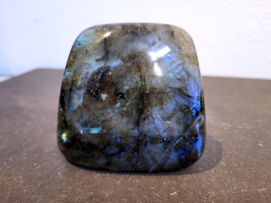 Labradoriet, 0,6kg, 8cm hoog, 17,- euro nr. 26
Beschrijving, Labradoriet.
Labradoriet is een edelsteen die bekend staat om zijn iriserende kleurenspel, ook wel labradoriseren genoemd, dat vaak doet denken aan het noorderlicht. Het is een populaire steen in de edelstenenwereld vanwege zowel zijn uiterlijk als zijn vermeende spirituele eigenschappen. 
Wat is labradoriet?
Labradoriet is een veldspaatmineraal dat wordt gekenmerkt door een opaalachtig glans of iriserend effect, veroorzaakt door de lichtbreking in de interne structuur van de steen.
De meest voorkomende kleur is grijs of groenachtig grijs, maar de steen kan ook blauwe, gele, oranje, paarse of zelfs rode flitsen laten zien.
De steen is genoemd naar het Canadese schiereiland Labrador, waar het voor het eerst werd ontdekt. 
Spirituele betekenis en eigenschappen:
Labradoriet wordt vaak beschouwd als een beschermende steen, vooral voor mensen die gevoelig zijn voor de energieën van hun omgeving. 
Het zou helpen bij het versterken van de aura en het verminderen van energielekkage, waardoor je je weerbaarder voelt. 
Labradoriet wordt geassocieerd met het versterken van intuïtie, het vergroten van het bewustzijn en het transformeren van negatieve energieën. 
Het wordt ook gebruikt om blokkades op te heffen en de innerlijke wijsheid te onthullen. 
Gebruik:
Labradoriet wordt vaak verwerkt in sieraden zoals hangers, armbanden en oorbellen. 
Het kan ook als ruwe steen, knuffelsteen of in andere vormen worden gebruikt, bijvoorbeeld in een huis of op een werkplek. 
Labradoriet kan worden gereinigd door het onder stromend water te houden of door het te reinigen met een andere steen zoals bergkristal of seleniet. 
Vindplaatsen:
Labradoriet wordt gevonden op verschillende locaties over de hele wereld, waaronder Canada, Finland, Madagaskar en Rusland. 
                                -Kunstgalerie Arnold-