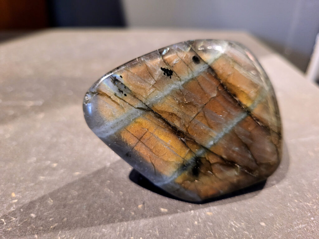 Labradoriet, 0,2kg, 7cm breed, 9,- euro, nr. 25
Beschrijving, Labradoriet.
Labradoriet is een edelsteen die bekend staat om zijn iriserende kleurenspel, ook wel labradoriseren genoemd, dat vaak doet denken aan het noorderlicht. Het is een populaire steen in de edelstenenwereld vanwege zowel zijn uiterlijk als zijn vermeende spirituele eigenschappen. 
Wat is labradoriet?
Labradoriet is een veldspaatmineraal dat wordt gekenmerkt door een opaalachtig glans of iriserend effect, veroorzaakt door de lichtbreking in de interne structuur van de steen.
De meest voorkomende kleur is grijs of groenachtig grijs, maar de steen kan ook blauwe, gele, oranje, paarse of zelfs rode flitsen laten zien.
De steen is genoemd naar het Canadese schiereiland Labrador, waar het voor het eerst werd ontdekt. 
Spirituele betekenis en eigenschappen:
Labradoriet wordt vaak beschouwd als een beschermende steen, vooral voor mensen die gevoelig zijn voor de energieën van hun omgeving. 
Het zou helpen bij het versterken van de aura en het verminderen van energielekkage, waardoor je je weerbaarder voelt. 
Labradoriet wordt geassocieerd met het versterken van intuïtie, het vergroten van het bewustzijn en het transformeren van negatieve energieën. 
Het wordt ook gebruikt om blokkades op te heffen en de innerlijke wijsheid te onthullen. 
Gebruik:
Labradoriet wordt vaak verwerkt in sieraden zoals hangers, armbanden en oorbellen. 
Het kan ook als ruwe steen, knuffelsteen of in andere vormen worden gebruikt, bijvoorbeeld in een huis of op een werkplek. 
Labradoriet kan worden gereinigd door het onder stromend water te houden of door het te reinigen met een andere steen zoals bergkristal of seleniet. 
Vindplaatsen:
Labradoriet wordt gevonden op verschillende locaties over de hele wereld, waaronder Canada, Finland, Madagaskar en Rusland. 
                                -Kunstgalerie Arnold-