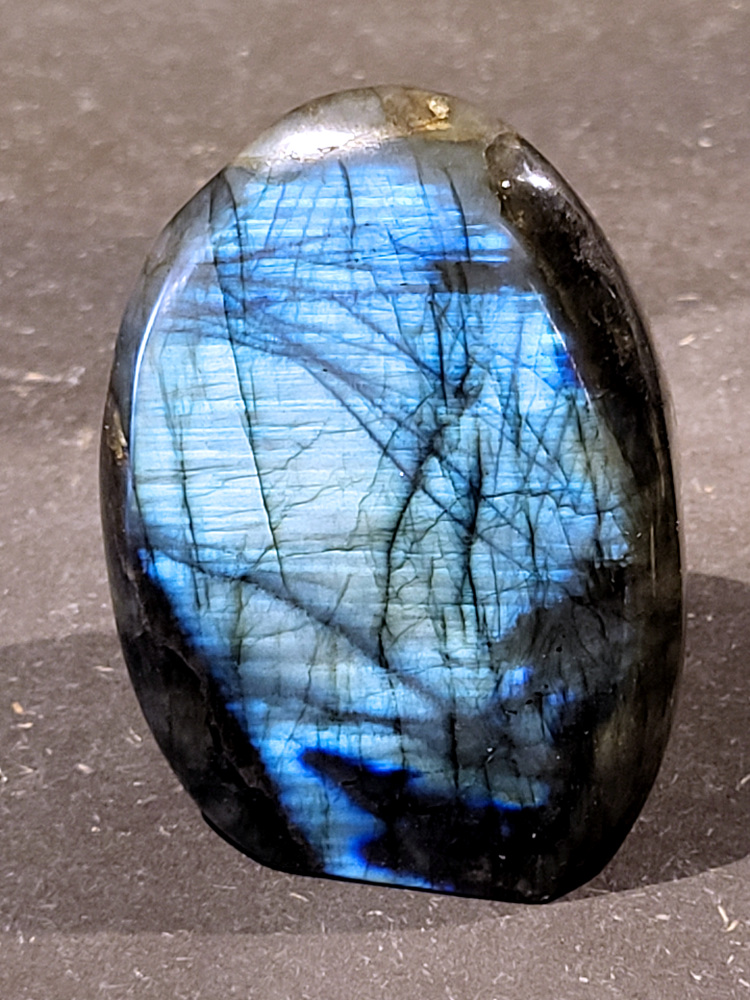 Labradoriet, 0,3kg, 7cm hoog, 15,- euro, nr. 58
Beschrijving, Labradoriet.
Labradoriet is een edelsteen die bekend staat om zijn iriserende kleurenspel, ook wel labradoriseren genoemd, dat vaak doet denken aan het noorderlicht. Het is een populaire steen in de edelstenenwereld vanwege zowel zijn uiterlijk als zijn vermeende spirituele eigenschappen. 
Wat is labradoriet?
Labradoriet is een veldspaatmineraal dat wordt gekenmerkt door een opaalachtig glans of iriserend effect, veroorzaakt door de lichtbreking in de interne structuur van de steen.
De meest voorkomende kleur is grijs of groenachtig grijs, maar de steen kan ook blauwe, gele, oranje, paarse of zelfs rode flitsen laten zien.
De steen is genoemd naar het Canadese schiereiland Labrador, waar het voor het eerst werd ontdekt. 
Spirituele betekenis en eigenschappen:
Labradoriet wordt vaak beschouwd als een beschermende steen, vooral voor mensen die gevoelig zijn voor de energieën van hun omgeving. 
Het zou helpen bij het versterken van de aura en het verminderen van energielekkage, waardoor je je weerbaarder voelt. 
Labradoriet wordt geassocieerd met het versterken van intuïtie, het vergroten van het bewustzijn en het transformeren van negatieve energieën. 
Het wordt ook gebruikt om blokkades op te heffen en de innerlijke wijsheid te onthullen. 
Gebruik:
Labradoriet wordt vaak verwerkt in sieraden zoals hangers, armbanden en oorbellen. 
Het kan ook als ruwe steen, knuffelsteen of in andere vormen worden gebruikt, bijvoorbeeld in een huis of op een werkplek. 
Labradoriet kan worden gereinigd door het onder stromend water te houden of door het te reinigen met een andere steen zoals bergkristal of seleniet. 
Vindplaatsen:
Labradoriet wordt gevonden op verschillende locaties over de hele wereld, waaronder Canada, Finland, Madagaskar en Rusland. 
                                -Kunstgalerie Arnold-