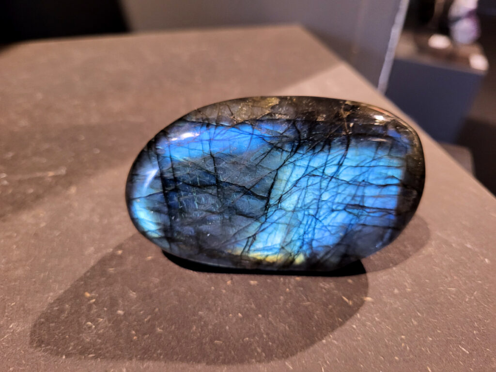 Labradoriet, 0,3kg, 9cm breed, 17,- euro, nr. 23
Beschrijving, Labradoriet.
Labradoriet is een edelsteen die bekend staat om zijn iriserende kleurenspel, ook wel labradoriseren genoemd, dat vaak doet denken aan het noorderlicht. Het is een populaire steen in de edelstenenwereld vanwege zowel zijn uiterlijk als zijn vermeende spirituele eigenschappen. 
Wat is labradoriet?
Labradoriet is een veldspaatmineraal dat wordt gekenmerkt door een opaalachtig glans of iriserend effect, veroorzaakt door de lichtbreking in de interne structuur van de steen.
De meest voorkomende kleur is grijs of groenachtig grijs, maar de steen kan ook blauwe, gele, oranje, paarse of zelfs rode flitsen laten zien.
De steen is genoemd naar het Canadese schiereiland Labrador, waar het voor het eerst werd ontdekt. 
Spirituele betekenis en eigenschappen:
Labradoriet wordt vaak beschouwd als een beschermende steen, vooral voor mensen die gevoelig zijn voor de energieën van hun omgeving. 
Het zou helpen bij het versterken van de aura en het verminderen van energielekkage, waardoor je je weerbaarder voelt. 
Labradoriet wordt geassocieerd met het versterken van intuïtie, het vergroten van het bewustzijn en het transformeren van negatieve energieën. 
Het wordt ook gebruikt om blokkades op te heffen en de innerlijke wijsheid te onthullen. 
Gebruik:
Labradoriet wordt vaak verwerkt in sieraden zoals hangers, armbanden en oorbellen. 
Het kan ook als ruwe steen, knuffelsteen of in andere vormen worden gebruikt, bijvoorbeeld in een huis of op een werkplek. 
Labradoriet kan worden gereinigd door het onder stromend water te houden of door het te reinigen met een andere steen zoals bergkristal of seleniet. 
Vindplaatsen:
Labradoriet wordt gevonden op verschillende locaties over de hele wereld, waaronder Canada, Finland, Madagaskar en Rusland. 
                                -Kunstgalerie Arnold-
