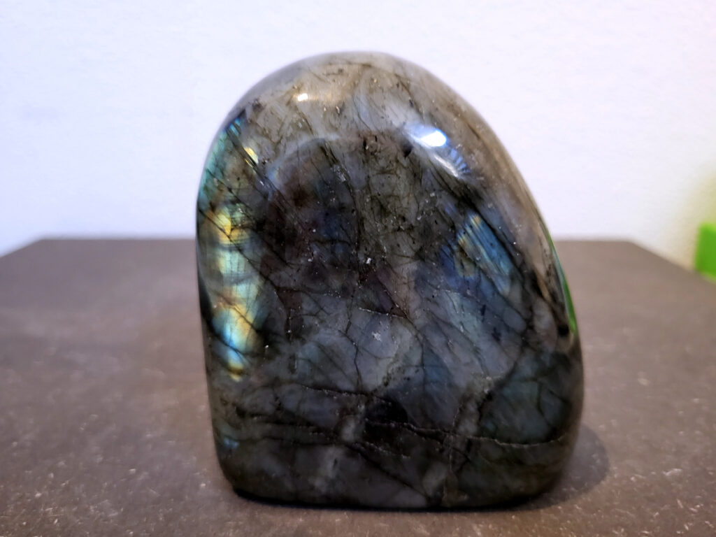 Labradoriet, 0,6kg, 9cm hoog, 18,- euro, nr. 21
Beschrijving, Labradoriet.
Labradoriet is een edelsteen die bekend staat om zijn iriserende kleurenspel, ook wel labradoriseren genoemd, dat vaak doet denken aan het noorderlicht. Het is een populaire steen in de edelstenenwereld vanwege zowel zijn uiterlijk als zijn vermeende spirituele eigenschappen. 
Wat is labradoriet?
Labradoriet is een veldspaatmineraal dat wordt gekenmerkt door een opaalachtig glans of iriserend effect, veroorzaakt door de lichtbreking in de interne structuur van de steen.
De meest voorkomende kleur is grijs of groenachtig grijs, maar de steen kan ook blauwe, gele, oranje, paarse of zelfs rode flitsen laten zien.
De steen is genoemd naar het Canadese schiereiland Labrador, waar het voor het eerst werd ontdekt. 
Spirituele betekenis en eigenschappen:
Labradoriet wordt vaak beschouwd als een beschermende steen, vooral voor mensen die gevoelig zijn voor de energieën van hun omgeving. 
Het zou helpen bij het versterken van de aura en het verminderen van energielekkage, waardoor je je weerbaarder voelt. 
Labradoriet wordt geassocieerd met het versterken van intuïtie, het vergroten van het bewustzijn en het transformeren van negatieve energieën. 
Het wordt ook gebruikt om blokkades op te heffen en de innerlijke wijsheid te onthullen. 
Gebruik:
Labradoriet wordt vaak verwerkt in sieraden zoals hangers, armbanden en oorbellen. 
Het kan ook als ruwe steen, knuffelsteen of in andere vormen worden gebruikt, bijvoorbeeld in een huis of op een werkplek. 
Labradoriet kan worden gereinigd door het onder stromend water te houden of door het te reinigen met een andere steen zoals bergkristal of seleniet. 
Vindplaatsen:
Labradoriet wordt gevonden op verschillende locaties over de hele wereld, waaronder Canada, Finland, Madagaskar en Rusland. 
                                -Kunstgalerie Arnold-