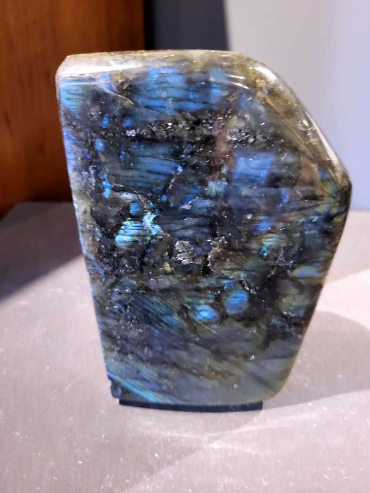 Labradoriet, 2,3kg, 17cm hoog, 81,- euro, nr. 54
Beschrijving, Labradoriet.
Labradoriet is een edelsteen die bekend staat om zijn iriserende kleurenspel, ook wel labradoriseren genoemd, dat vaak doet denken aan het noorderlicht. Het is een populaire steen in de edelstenenwereld vanwege zowel zijn uiterlijk als zijn vermeende spirituele eigenschappen. 
Wat is labradoriet?
Labradoriet is een veldspaatmineraal dat wordt gekenmerkt door een opaalachtig glans of iriserend effect, veroorzaakt door de lichtbreking in de interne structuur van de steen.
De meest voorkomende kleur is grijs of groenachtig grijs, maar de steen kan ook blauwe, gele, oranje, paarse of zelfs rode flitsen laten zien.
De steen is genoemd naar het Canadese schiereiland Labrador, waar het voor het eerst werd ontdekt. 
Spirituele betekenis en eigenschappen:
Labradoriet wordt vaak beschouwd als een beschermende steen, vooral voor mensen die gevoelig zijn voor de energieën van hun omgeving. 
Het zou helpen bij het versterken van de aura en het verminderen van energielekkage, waardoor je je weerbaarder voelt. 
Labradoriet wordt geassocieerd met het versterken van intuïtie, het vergroten van het bewustzijn en het transformeren van negatieve energieën. 
Het wordt ook gebruikt om blokkades op te heffen en de innerlijke wijsheid te onthullen. 
Gebruik:
Labradoriet wordt vaak verwerkt in sieraden zoals hangers, armbanden en oorbellen. 
Het kan ook als ruwe steen, knuffelsteen of in andere vormen worden gebruikt, bijvoorbeeld in een huis of op een werkplek. 
Labradoriet kan worden gereinigd door het onder stromend water te houden of door het te reinigen met een andere steen zoals bergkristal of seleniet. 
Vindplaatsen:
Labradoriet wordt gevonden op verschillende locaties over de hele wereld, waaronder Canada, Finland, Madagaskar en Rusland. 
                                -Kunstgalerie Arnold-